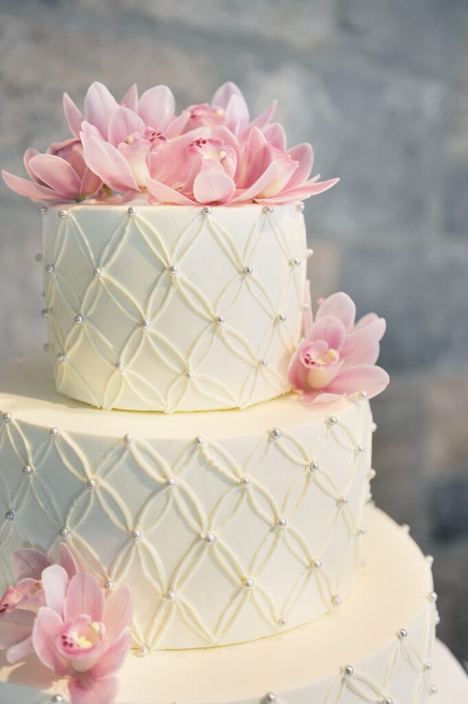Pink orchids decorating a three-tier buttercream decorated white wedding cake at Tappan Hill Mansion in Tarrytown.