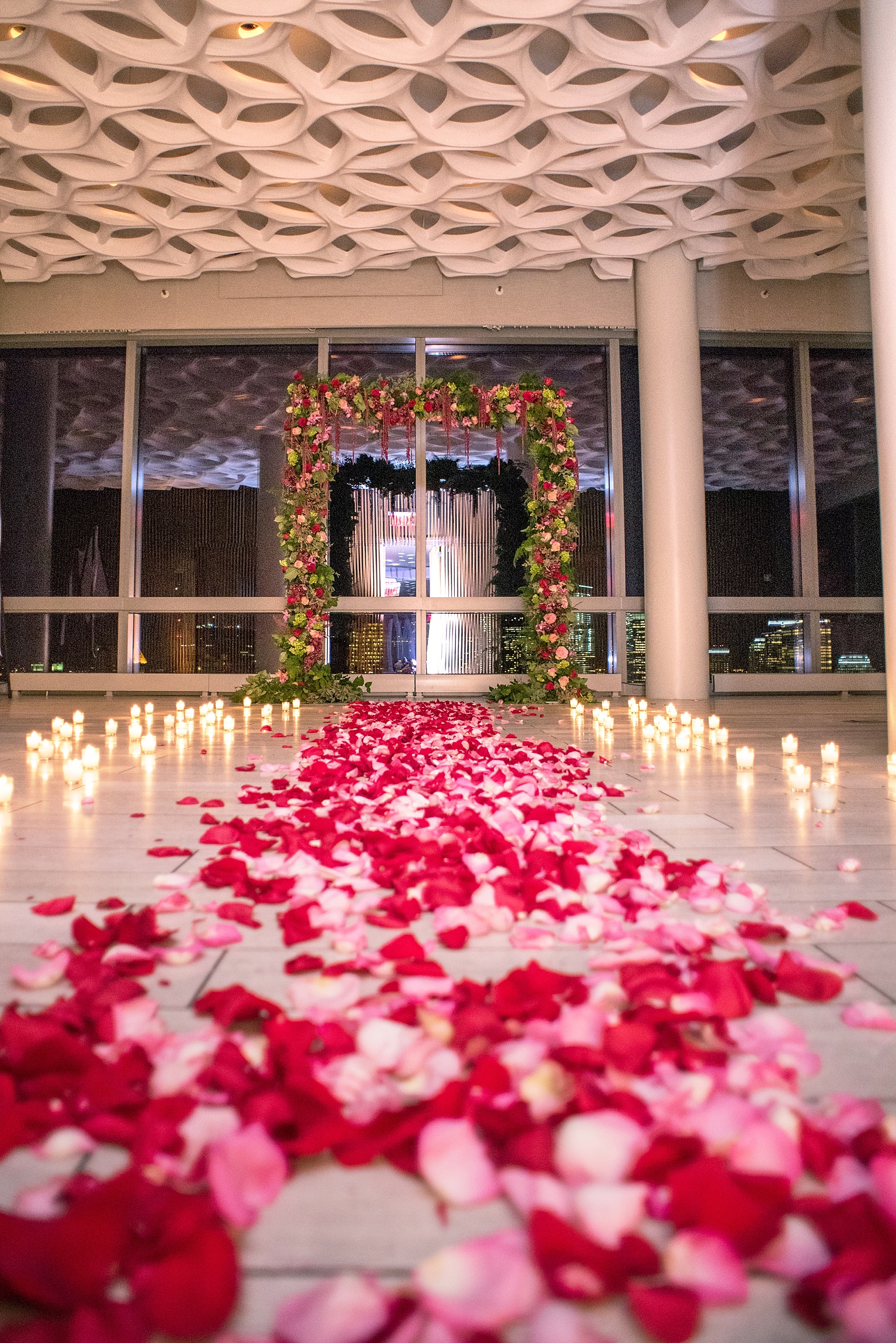 NYC Proposal Photos by Mikkel Paige Photography. Candlelight rose aisle at Trump Soho overlooking NYC skyline. Flowers by The Arrangement NYC. 