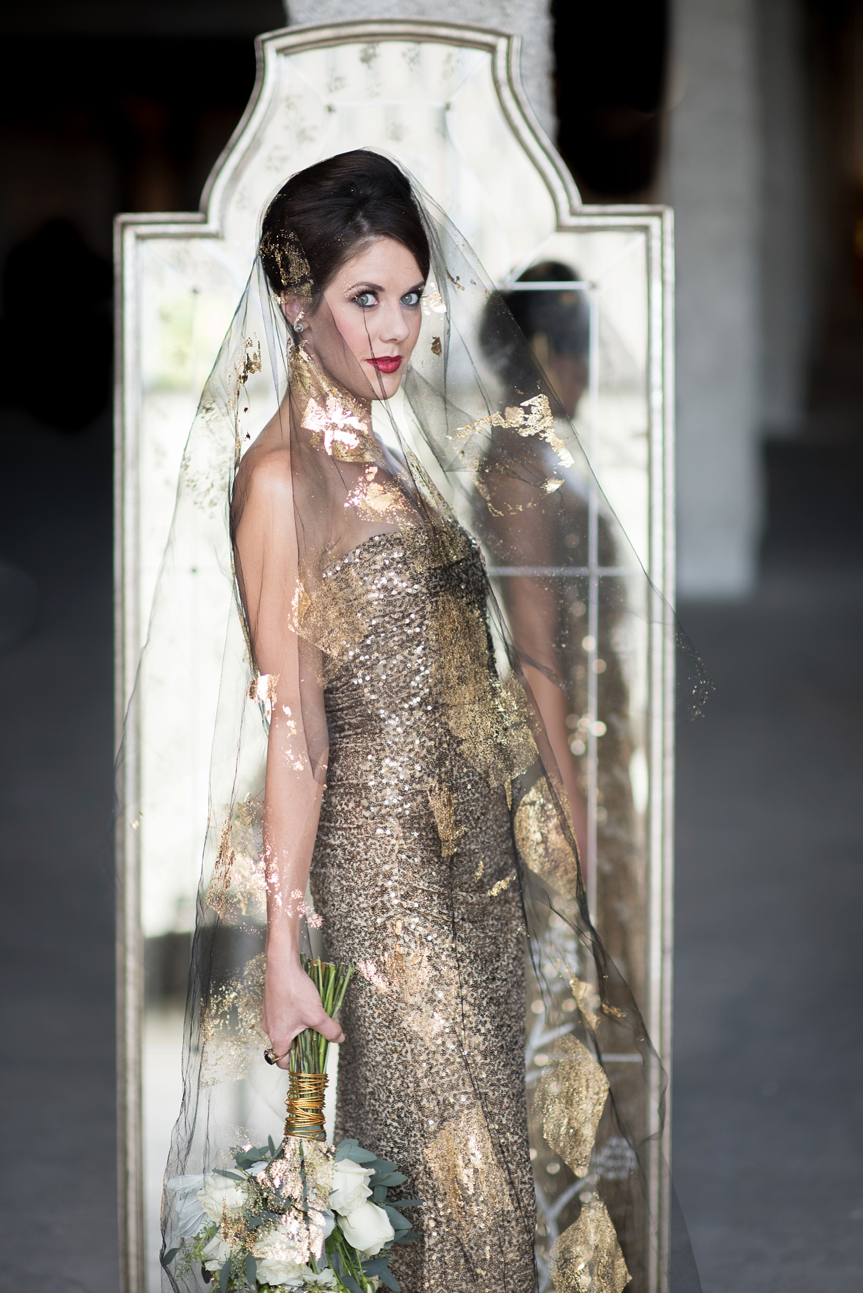 Destination wedding photographer Mikkel Paige captures a glamorous industrial bridal session in Hawaii with Burnett's Boards and Moana Events. Gold sequin gown from Rent the Runway with the bride in a black veil and gold and white bouquet.