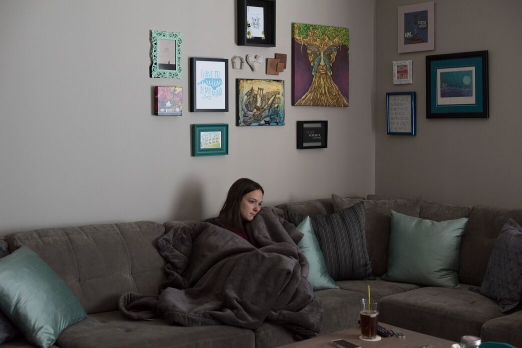 Raleigh wedding photographer Mikkel Paige relaxing on the couch with a collage wall.