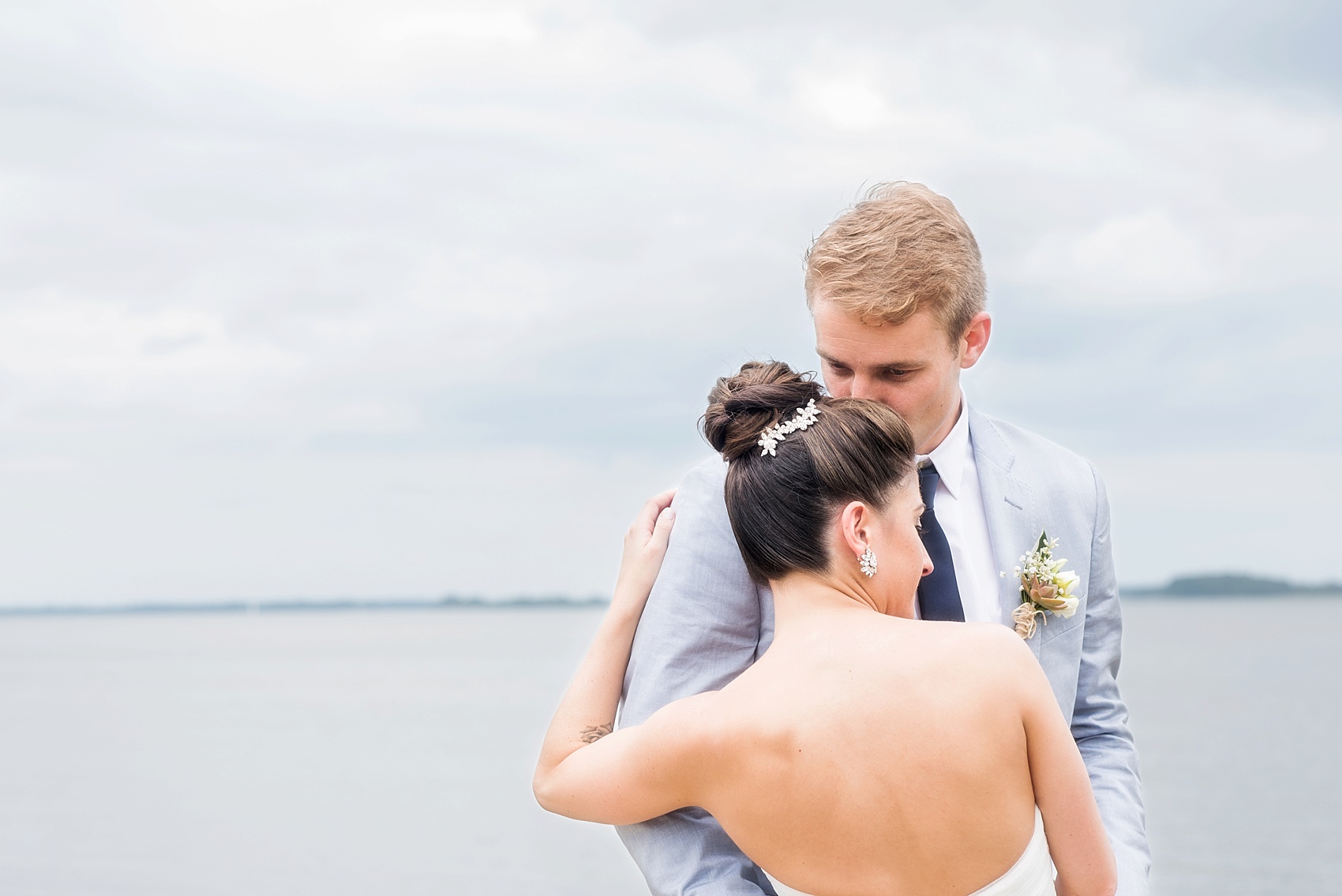 Hilton Head Island wedding photographer, Mikkel Paige, captures a wedding party at Daufuskie Island, Haig Point. Bridesmaids in blush pink dresses and groomsmen in navy blue suits. The couple shares a beach embrace.