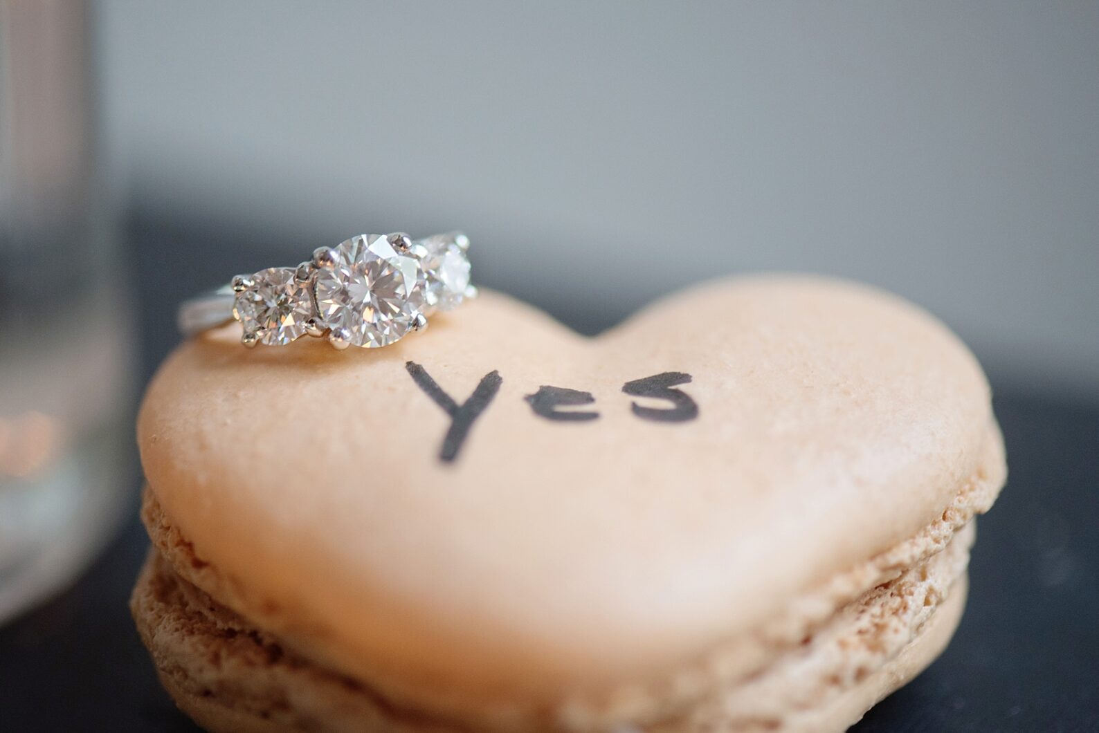 "Yes" peach heart macaron for a NYC Proposal in Chelsea, Haven's Kitchen. Three round diamond engagement ring, with photos by NYC wedding photographer Mikkel Paige. Flowers by The Arrangement, planning by Brilliant Event Planning.