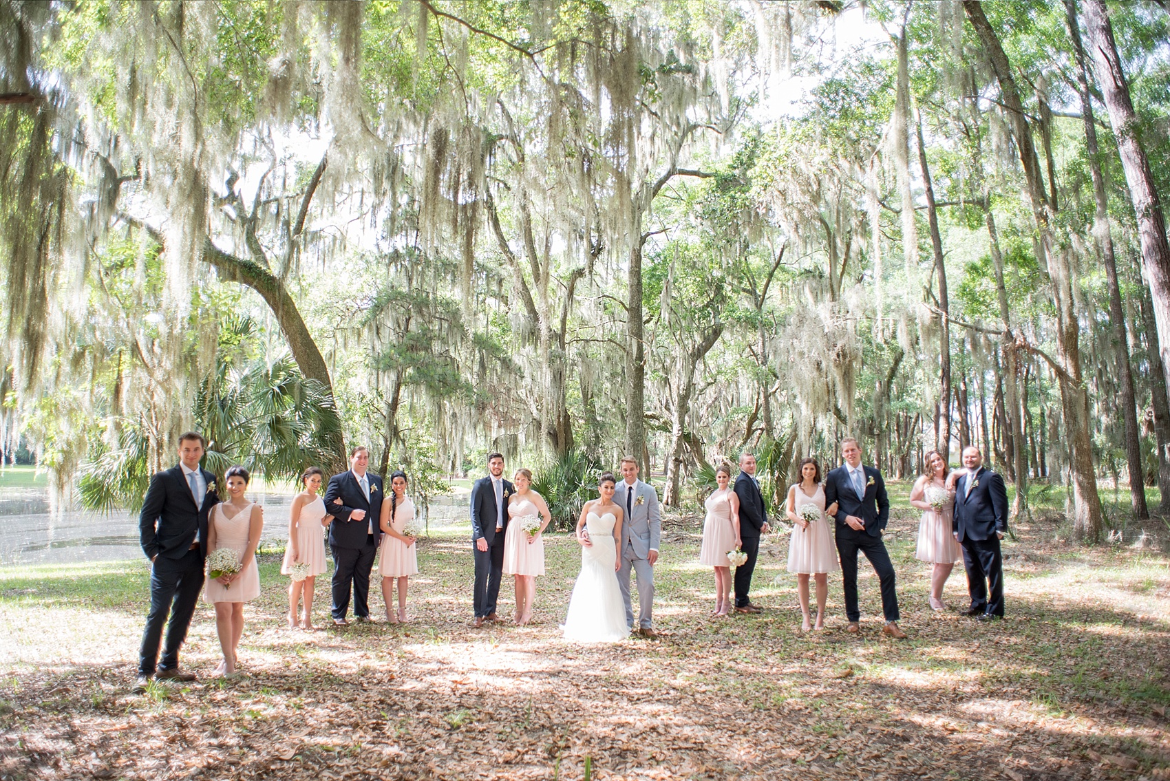 Groomsmen in navy Zara suits and bridesmaids in short pink Bill Levkoff dresses. Wedding party at Haig Point, South Carolina, off the coast of Hilton Head. Photos by Mikkel Paige Photography. Baby's breath bouquets and succulent boutonnieres complete the look.