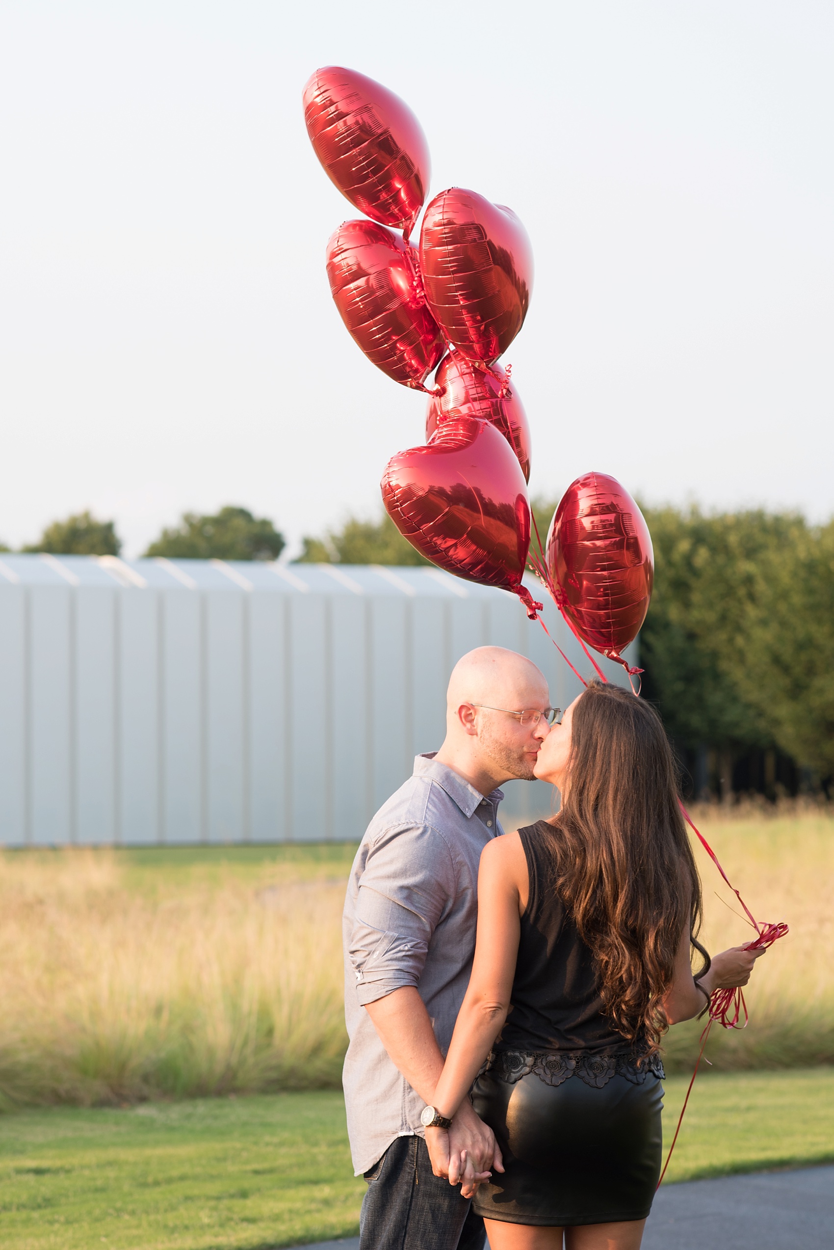 Raleigh wedding photographer captures a couple and heart balloons at their sunset engagement session.