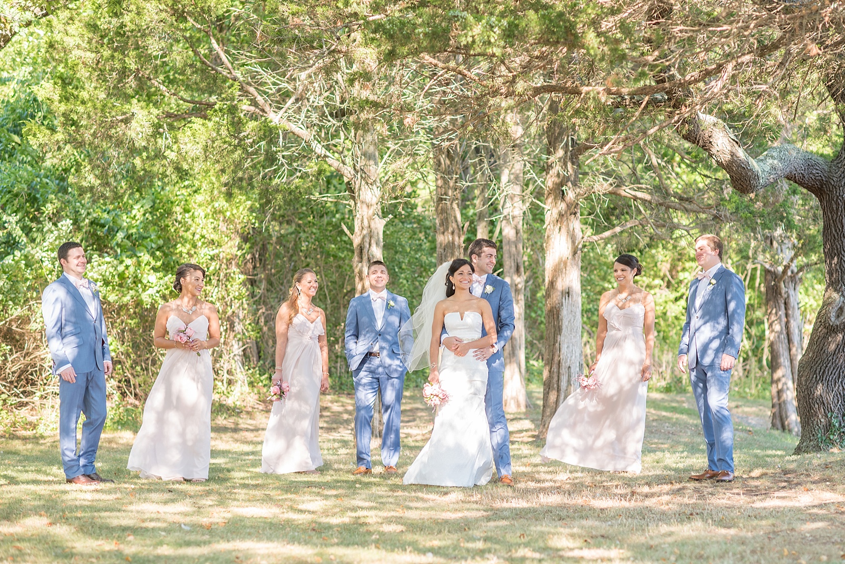 Connecticut beach wedding photos by Mikkel Paige Photography. Groomsmen in blue suits and pink bow ties and bridesmaids in blush chiffon gowns.