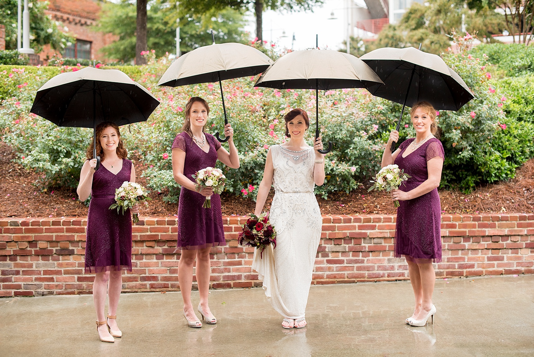 Wedding party photos in the rain! Burgundy bridesmaids with bride in beaded 1920s art deco gown. Bay 7 Durham, NC wedding. Photos by Mikkel Paige Photography. 