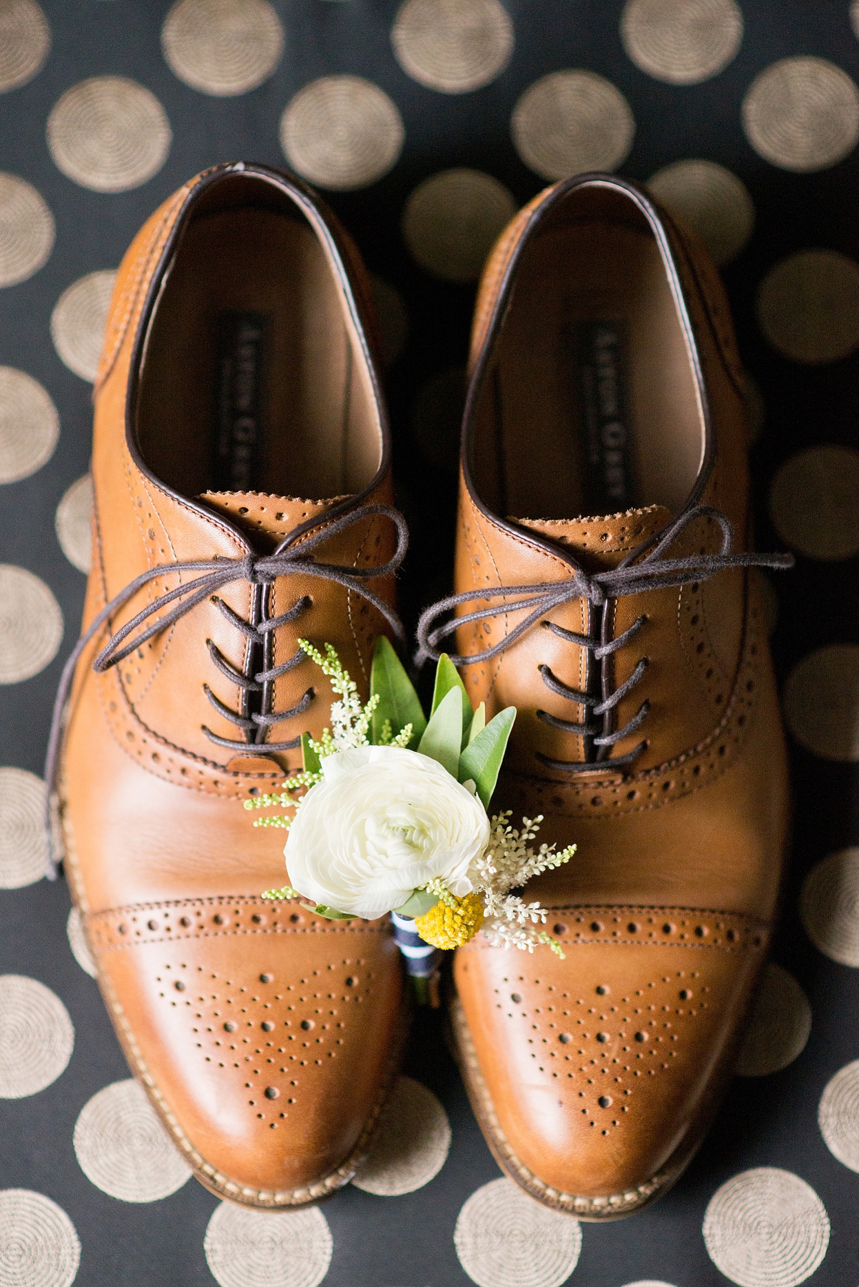 Groom gets ready with his brown shoes and ranunculus boutonniere at the Molly Pitcher Inn. Photo by Mikkel Paige Photography.