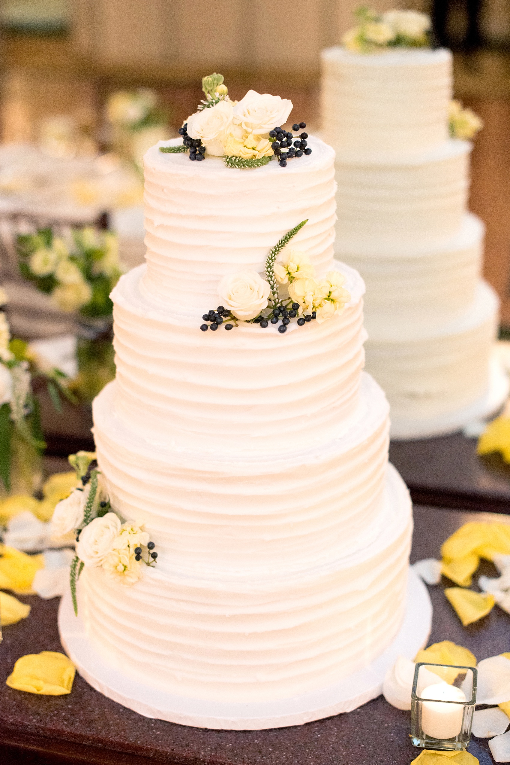 White buttercream wedding cake with yellow, white and blue flowers at the Molly Pitcher Inn. Photo by Mikkel Paige Photography.