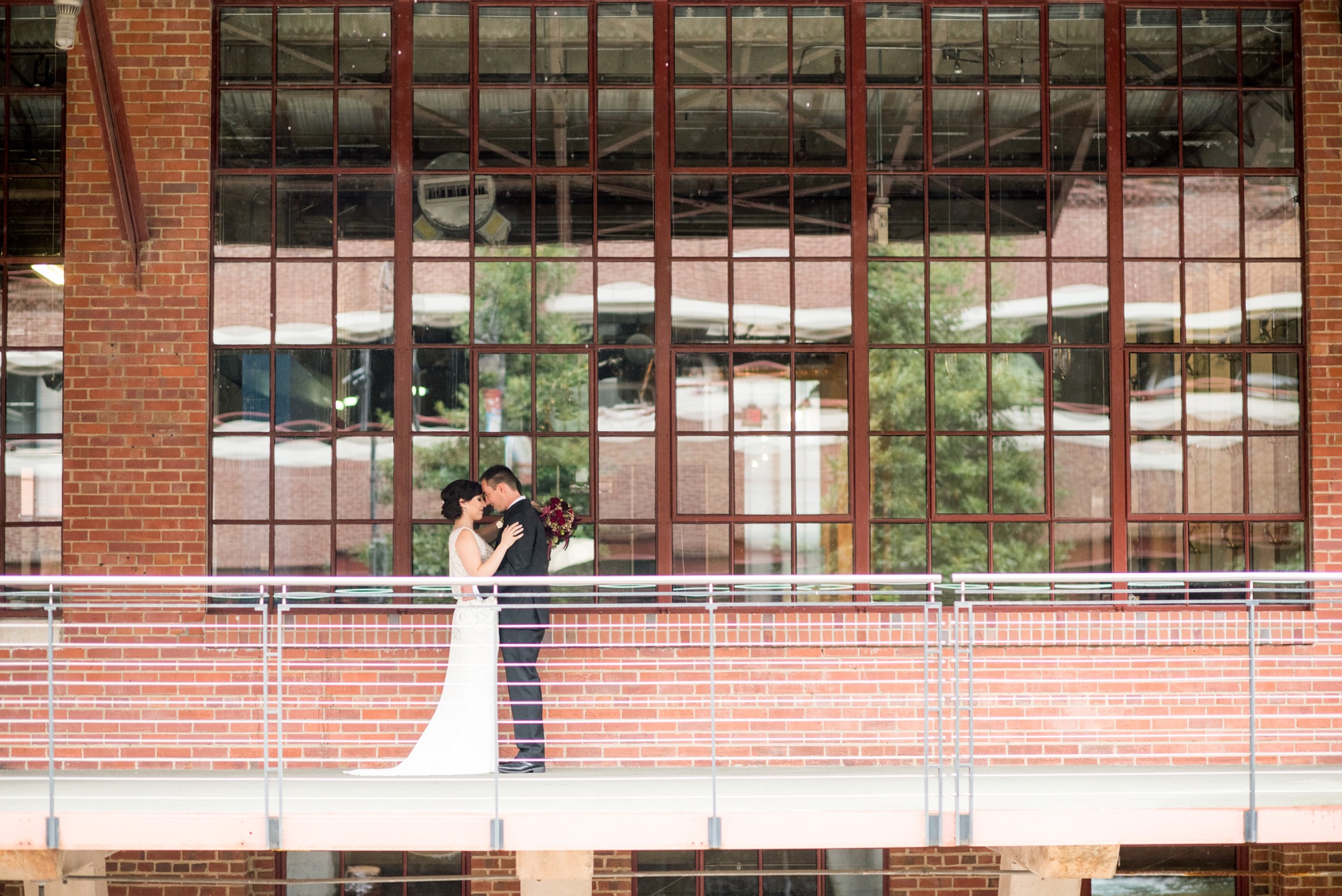 Bay 7 wedding photos by Mikkel Paige Photography. Raleigh wedding photographer captures the bride and groom's industrial outdoor portraits in the rain with an umbrella.