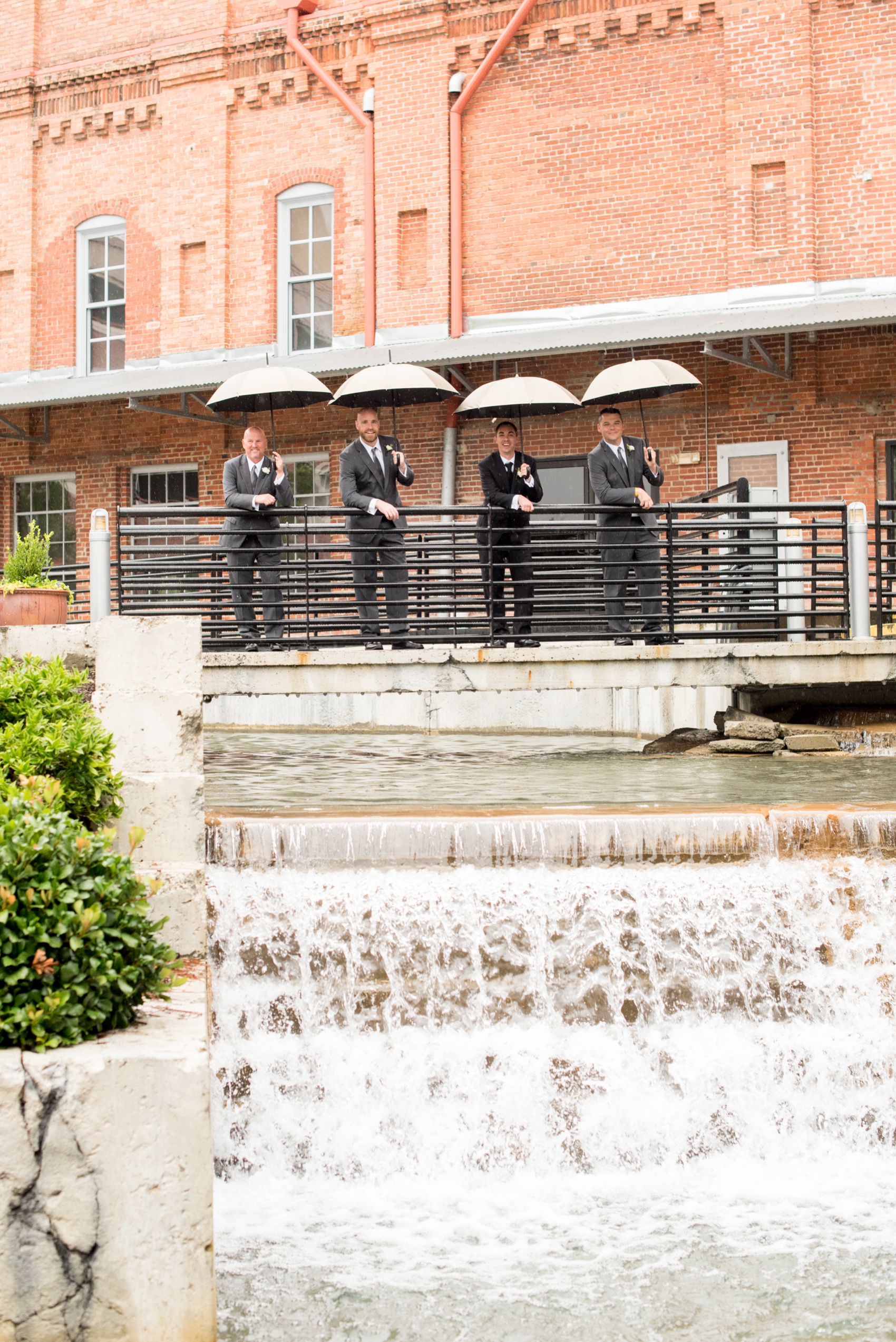 Bay 7 wedding photos by Mikkel Paige Photography. Raleigh wedding photographer captures the groomsmen in the rain with umbrellas.