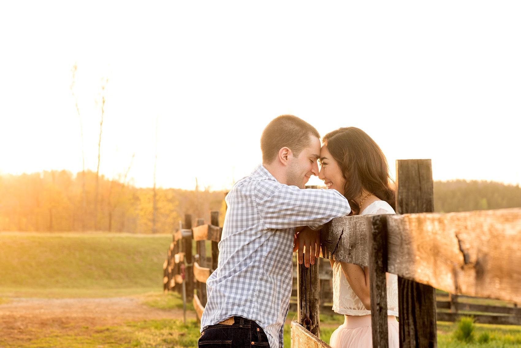 Raleigh farm engagement photos during the golden hour with a wooden fence during the golden hour. Images by Mikkel Paige Photography.