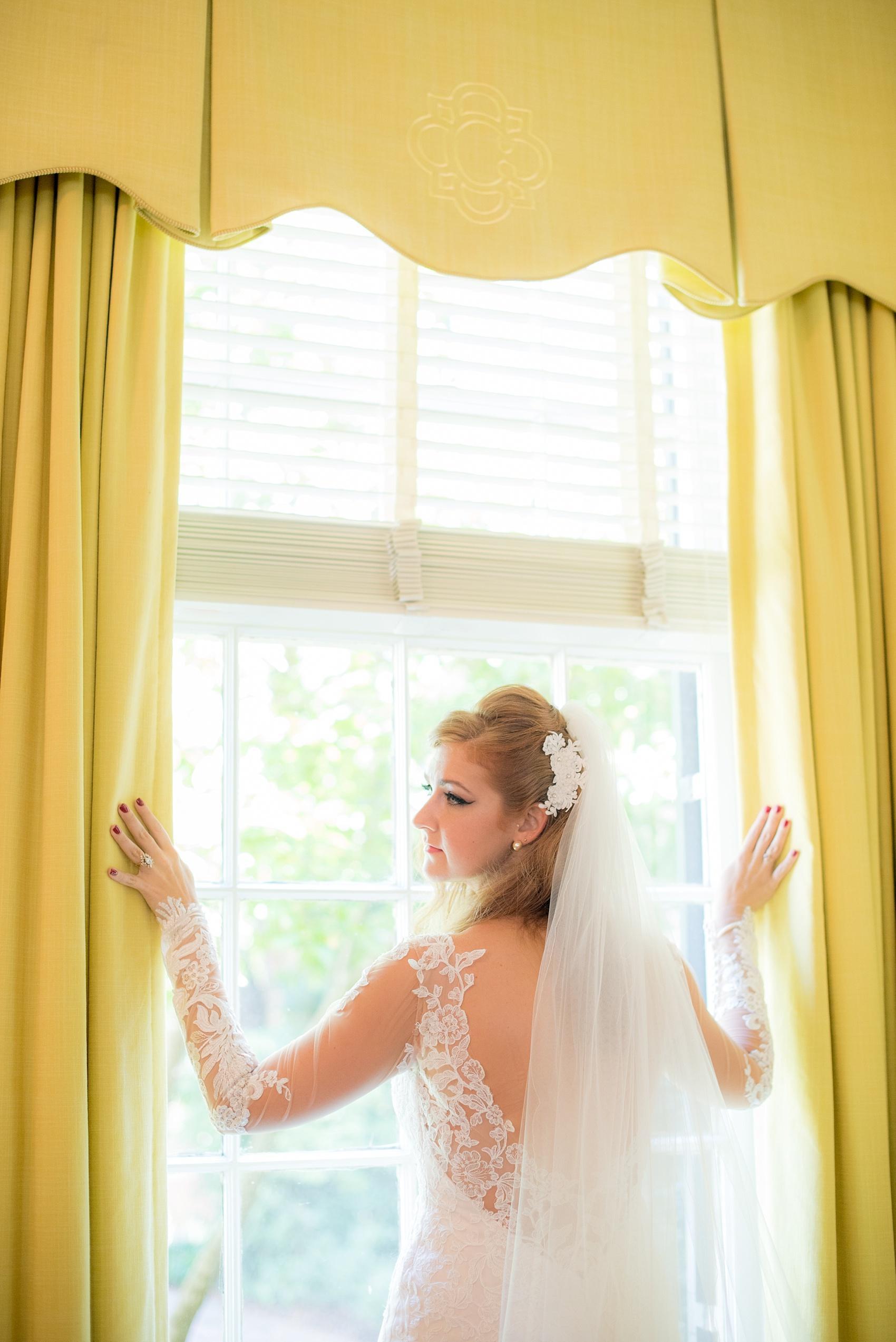 The Carolina Inn bridal portraits by Raleigh wedding photographer Mikkel Paige Photography. The bride in a white lace gown with lush yellow curtains.