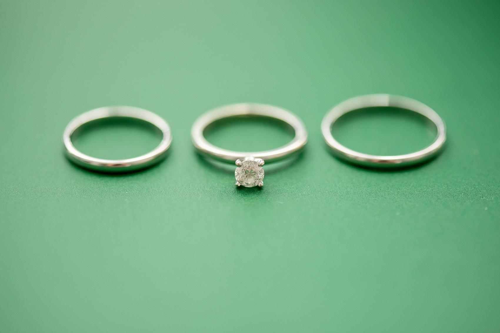 White gold wedding bands and solitaire diamond engagement ring on a green background at a Four Oaks Manor wedding in Atlanta. Images by Mikkel Paige Photography.