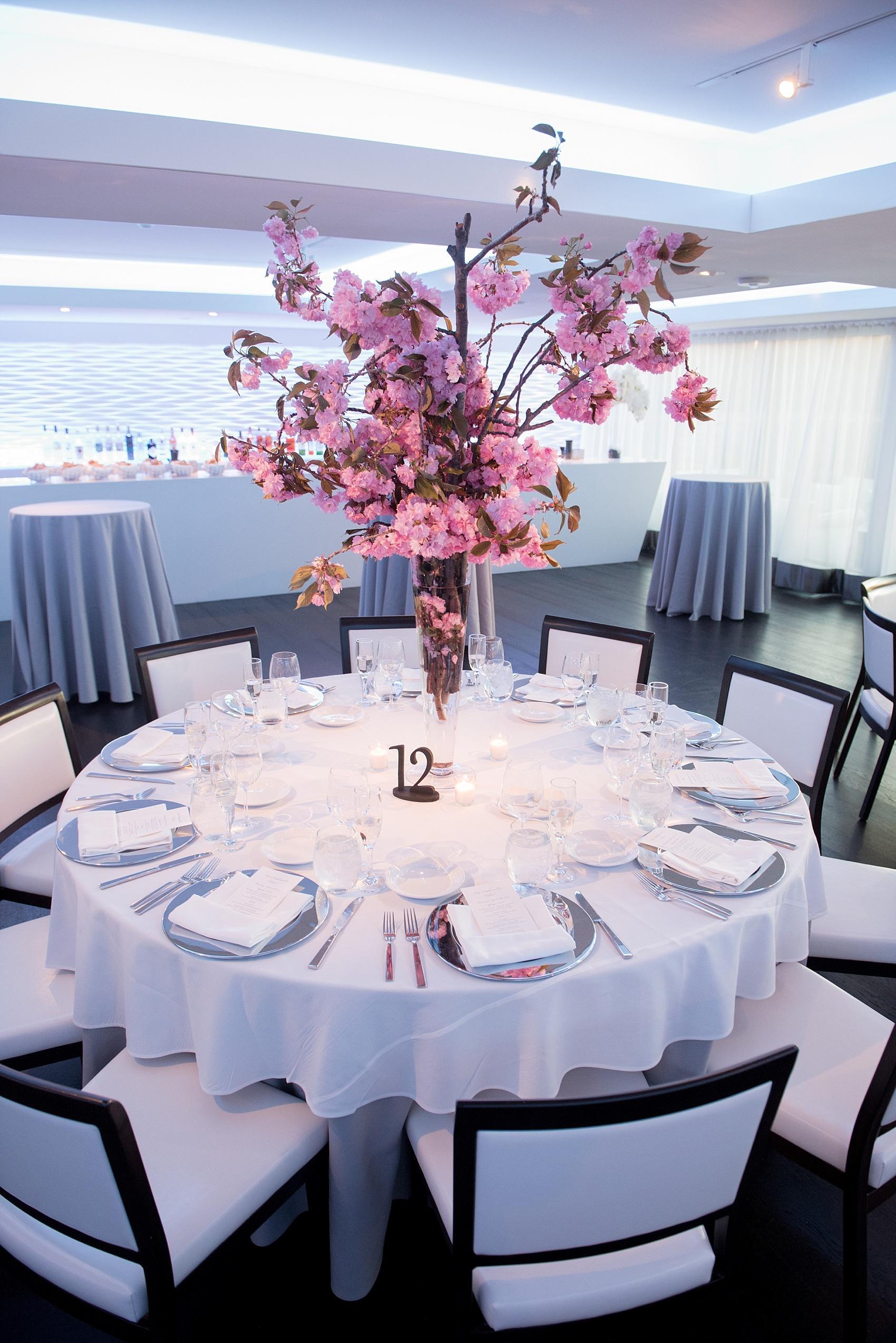 Photos by Mikkel Paige Photography for a wedding at Harbor Club on Long Island. Modern sleek reception tables decorated with cherry blossoms centerpieces.