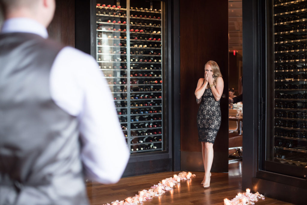 NYC Proposal Photographer Mikkel Paige Photography captures a travel themed marriage proposal in Columbus Circle with calligraphy on paper airplanes, rose petals and candles on the floor.