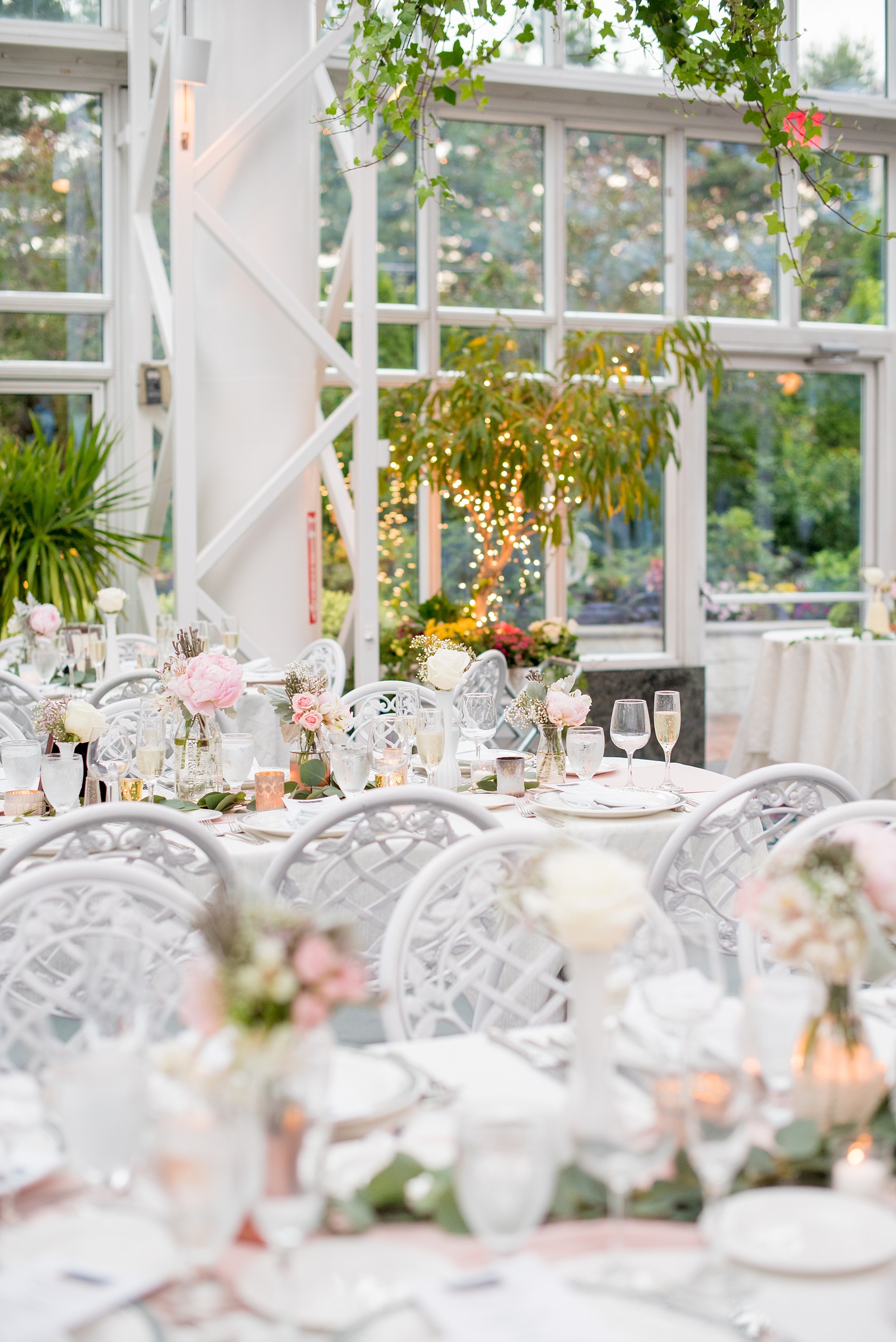 Mikkel Paige Photography photo of a wedding at the Madison Hotel in NJ. Photo of the white table at the reception in The Conservatory with pink peonies in bud vases.