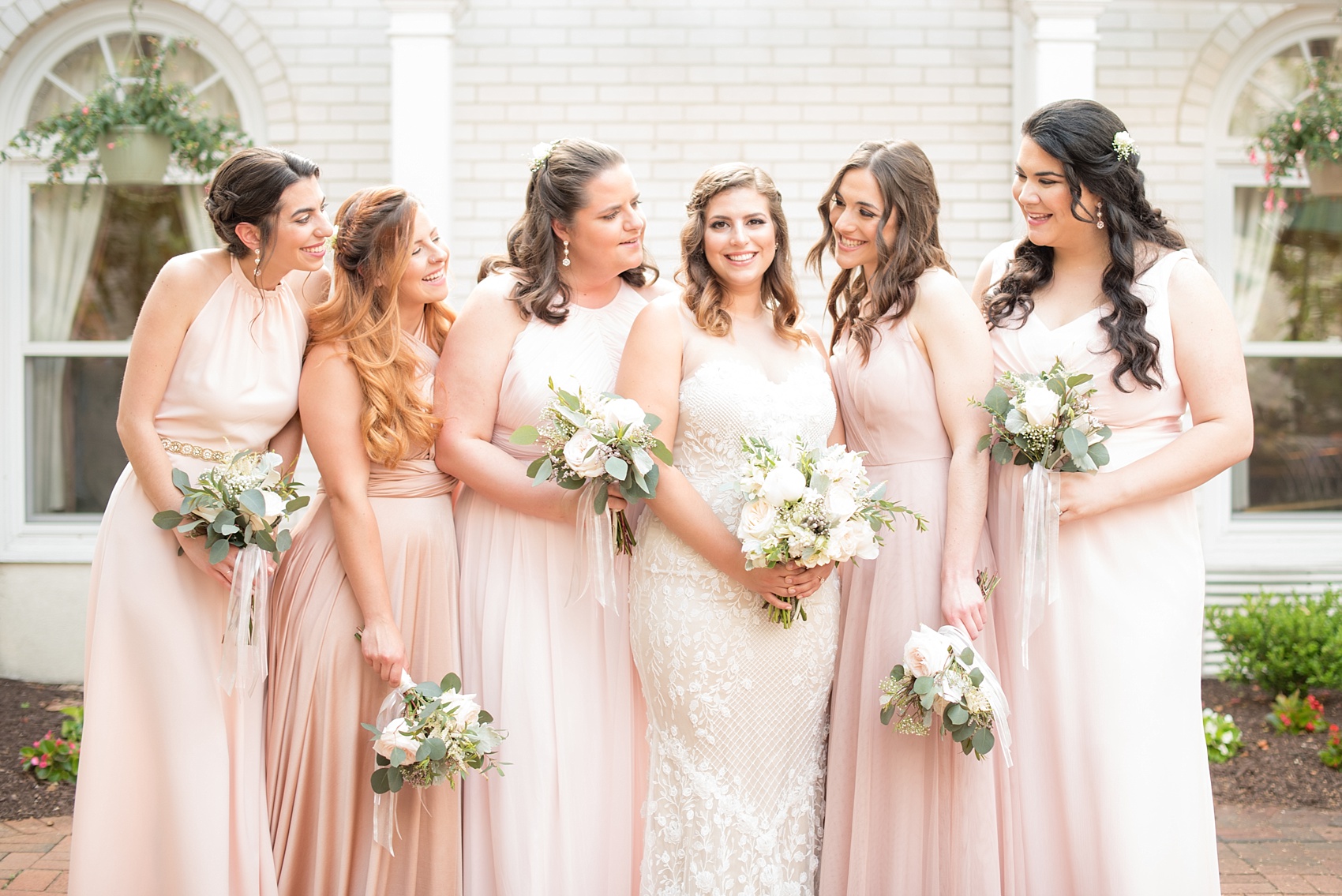 Mikkel Paige Photography photo of a wedding at Madison Hotel in NJ with the bridal party in light pink mismatched dresses with white rose and eucalyptus bouquets with long ribbons and the bride in a beaded BHLDN gown.
