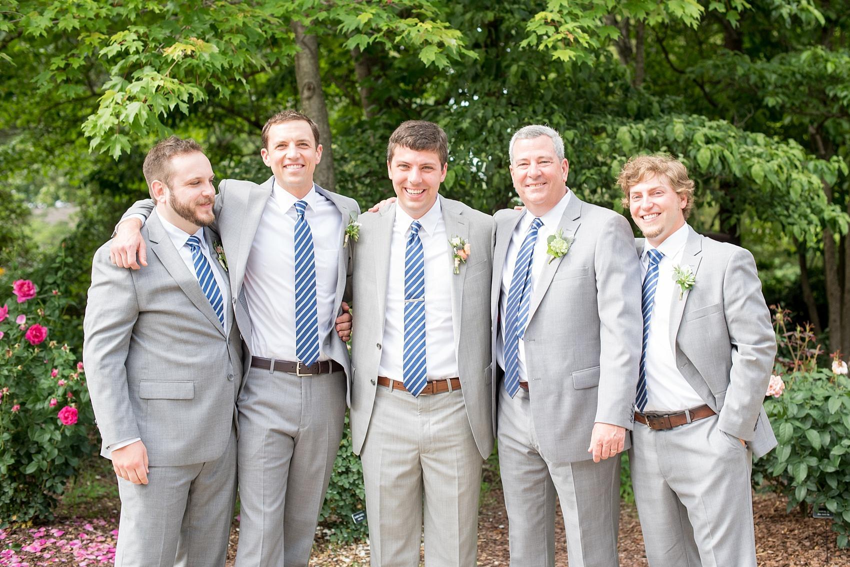 Mikkel Paige Photography pictures of a wedding in downtown Raleigh. Photo of the groom and groomsmen in grey suits with blue ties.