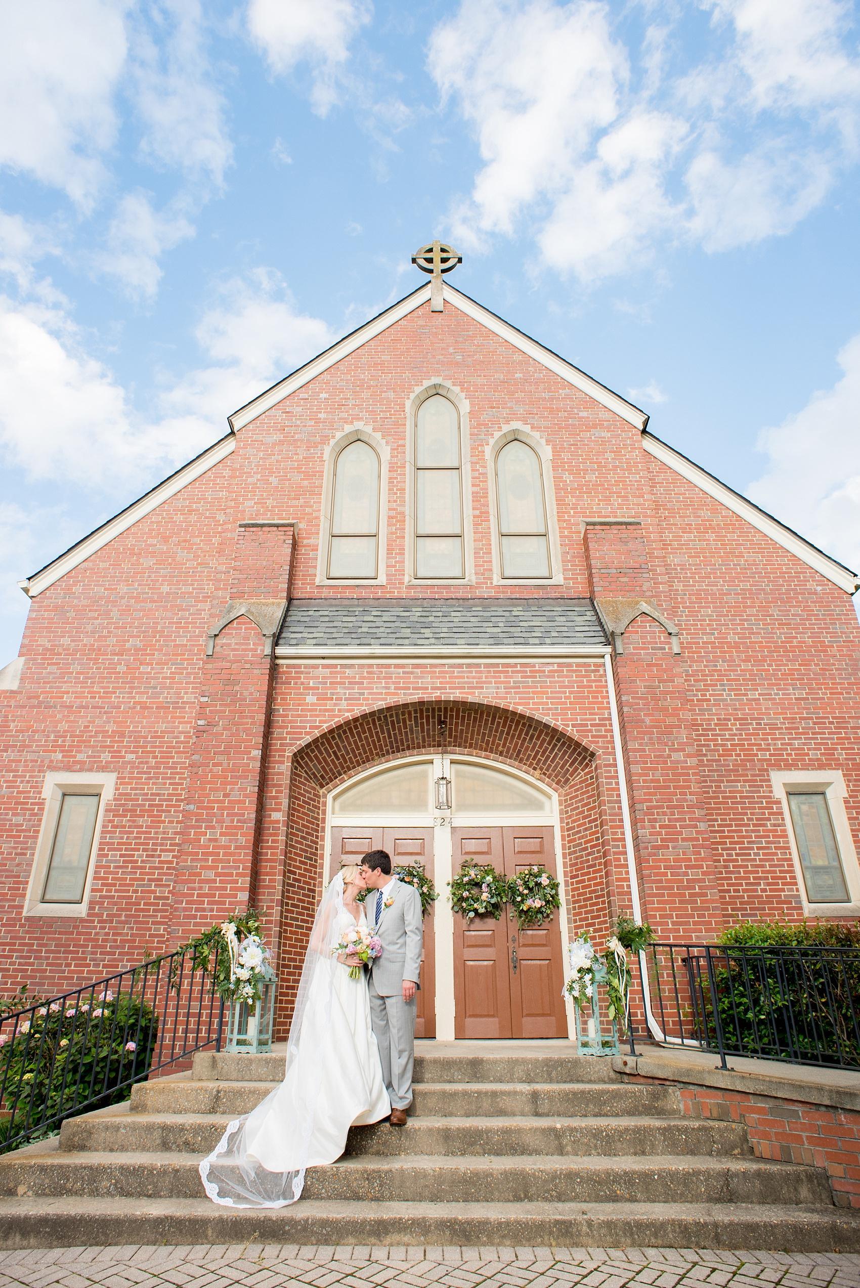 Mikkel Paige Photography photos of a downtown Raleigh wedding. Light blue details with planning by Sally Oakley. Iconic ceremony image of the bride and groom kissing in front of the church.