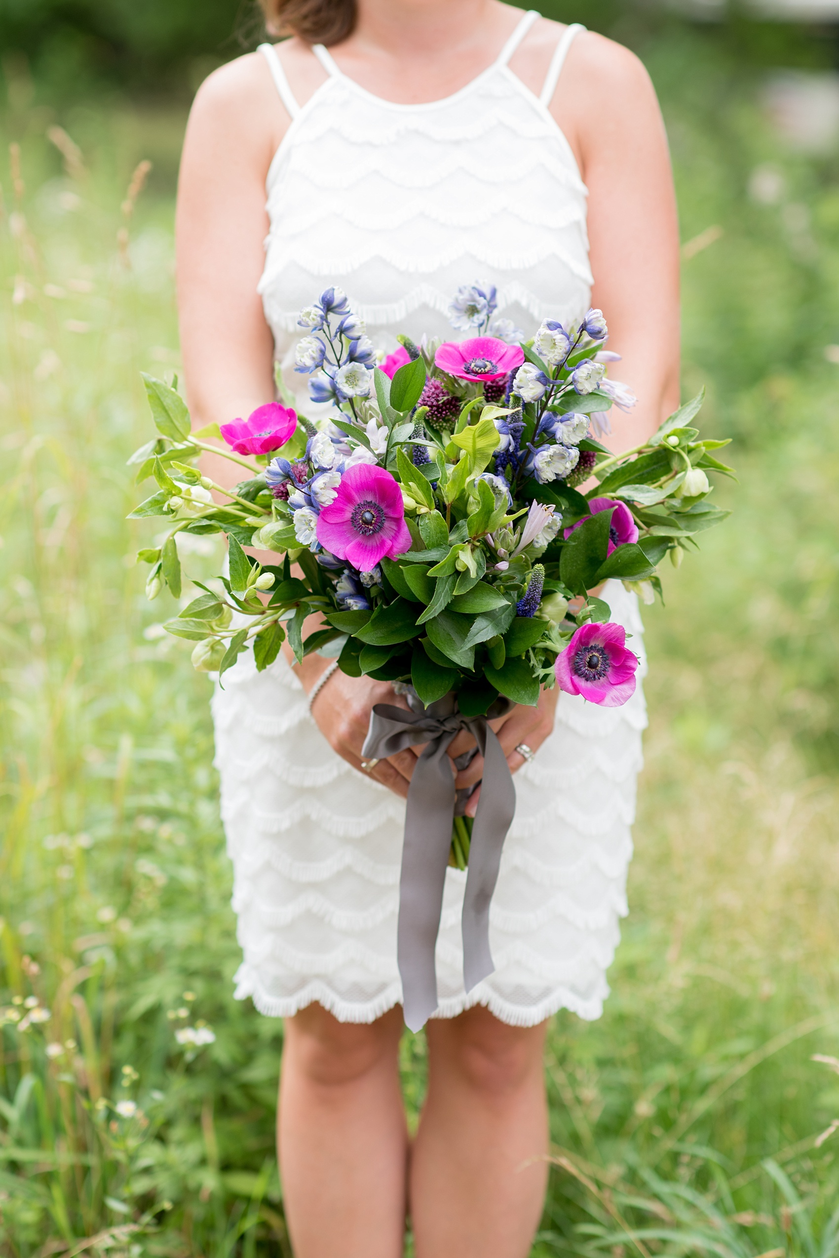 Mikkel Paige Photography photo of an anniversary session with a colorful bouquet of fuchsia and purple, including anemones, larkspur, helliborus and veronica flowers.