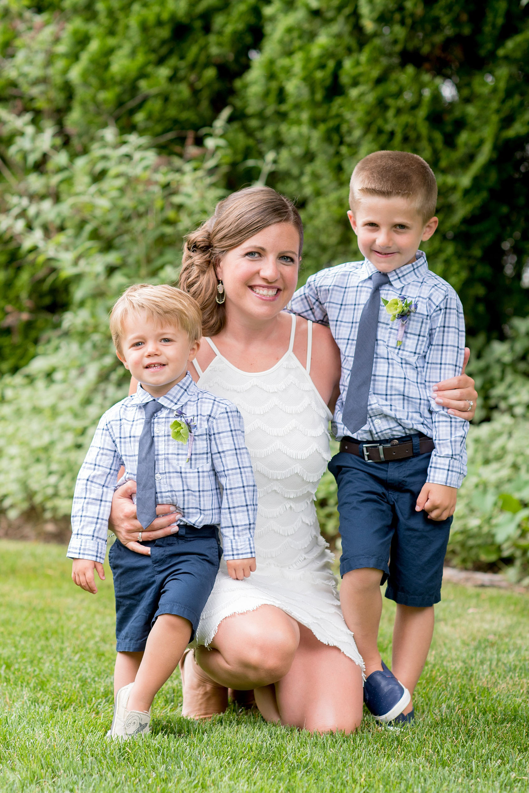 Mikkel Paige Photography photo of an anniversary session with the bride and groom in a short white dress and blue suit, with their sons as ring bearers in plaid shirts and navy ties.