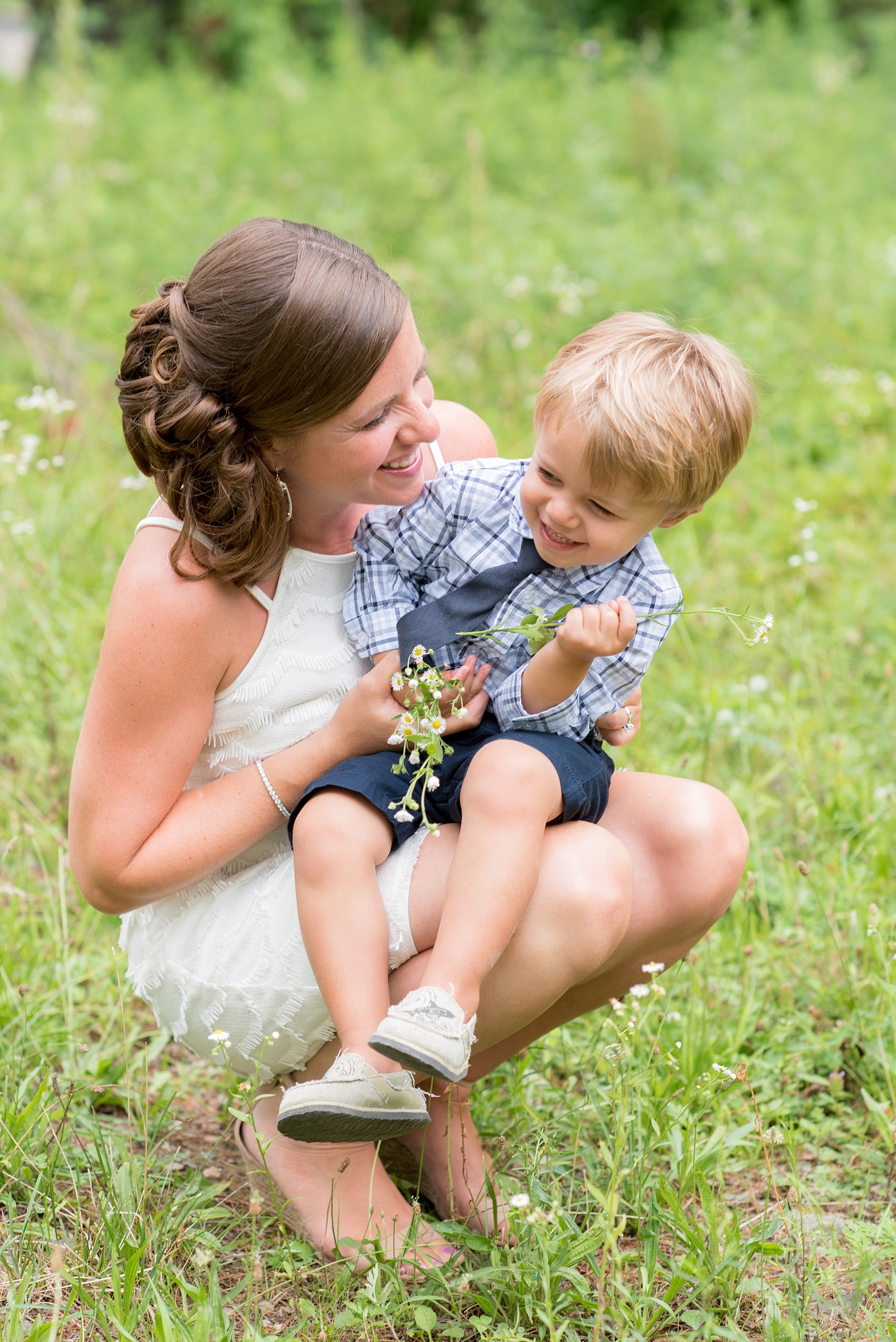 Mikkel Paige Photography photo of an anniversary session with the bride and groom's son ring bearers in plaid shirts and navy tie in a flower field.