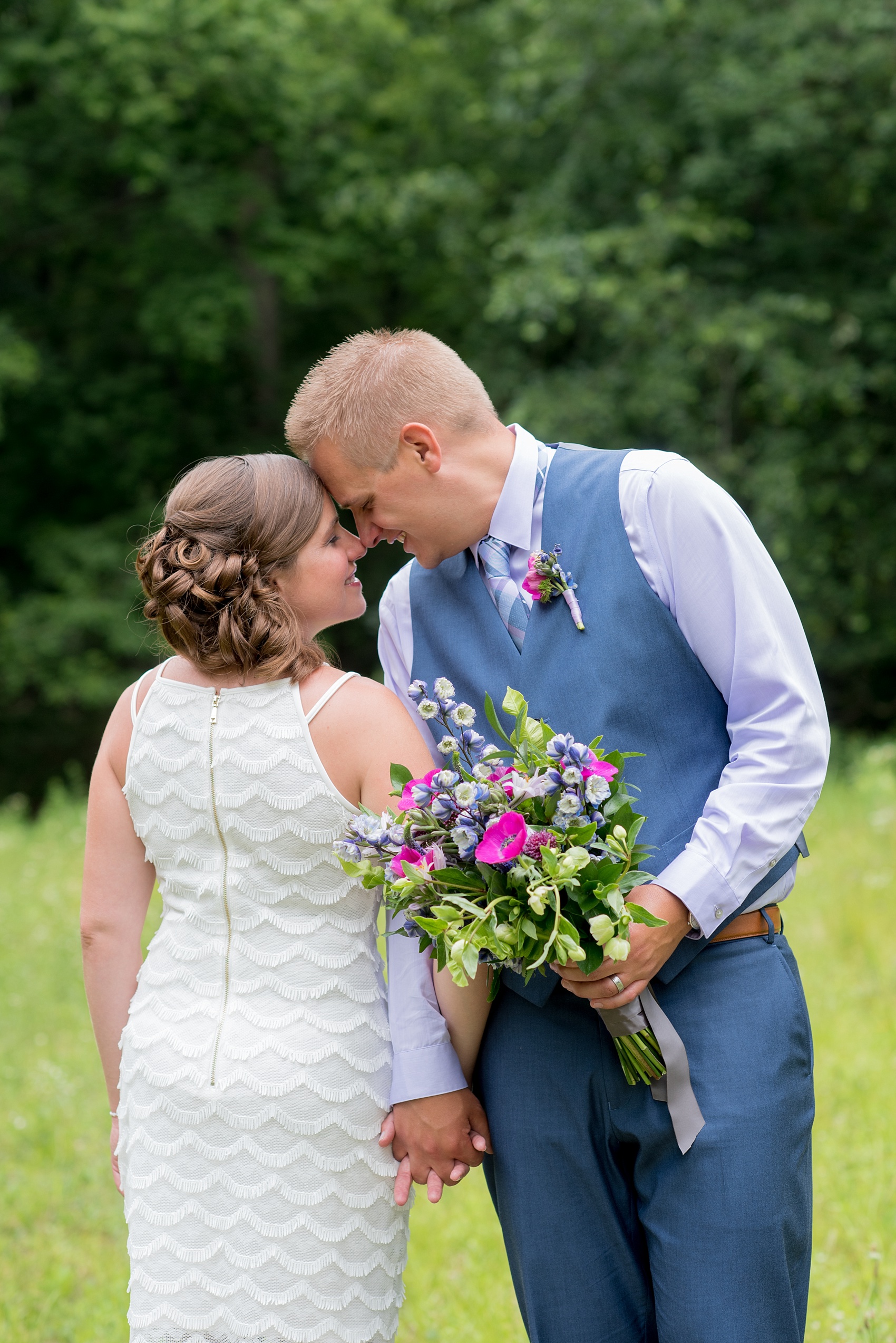 Mikkel Paige Photography photo of an anniversary session with light blue, navy and fuchsia pink accents with a bride and groom in a short white dress and blue suit and vest. 