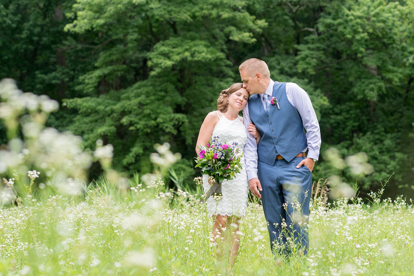 Mikkel Paige Photography photo of an anniversary session with light blue, navy and fuchsia pink accents with a bride and groom in a short white dress and blue suit and vest. 