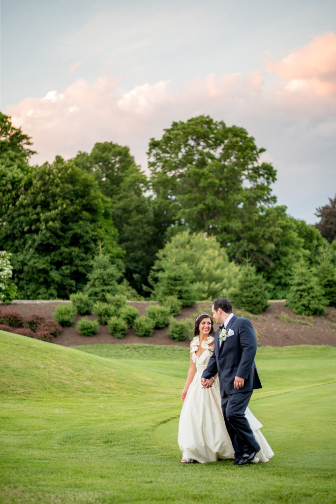 Mikkel Paige Photography photos from a wedding at Basking Ridge Country Club, NJ. The bride in a halter Amsale gown and groom in a navy blue suit at a picturesque pink and blue sunset on the golf course.