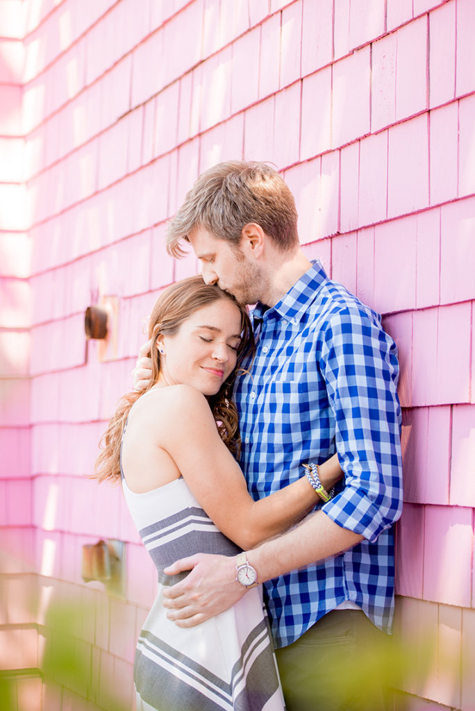 Mikkel Paige Photography beach engagement photos in Bay Head, NJ. Bride and groom next to a pink shingle hotel.