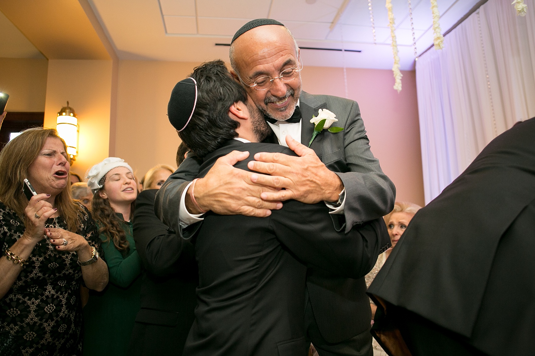 Mikkel Paige Photography photo of the groom and bride's father hugging at the bedekan during a traditional Jewish ceremony at Temple Emanu-El in Closter, NJ.