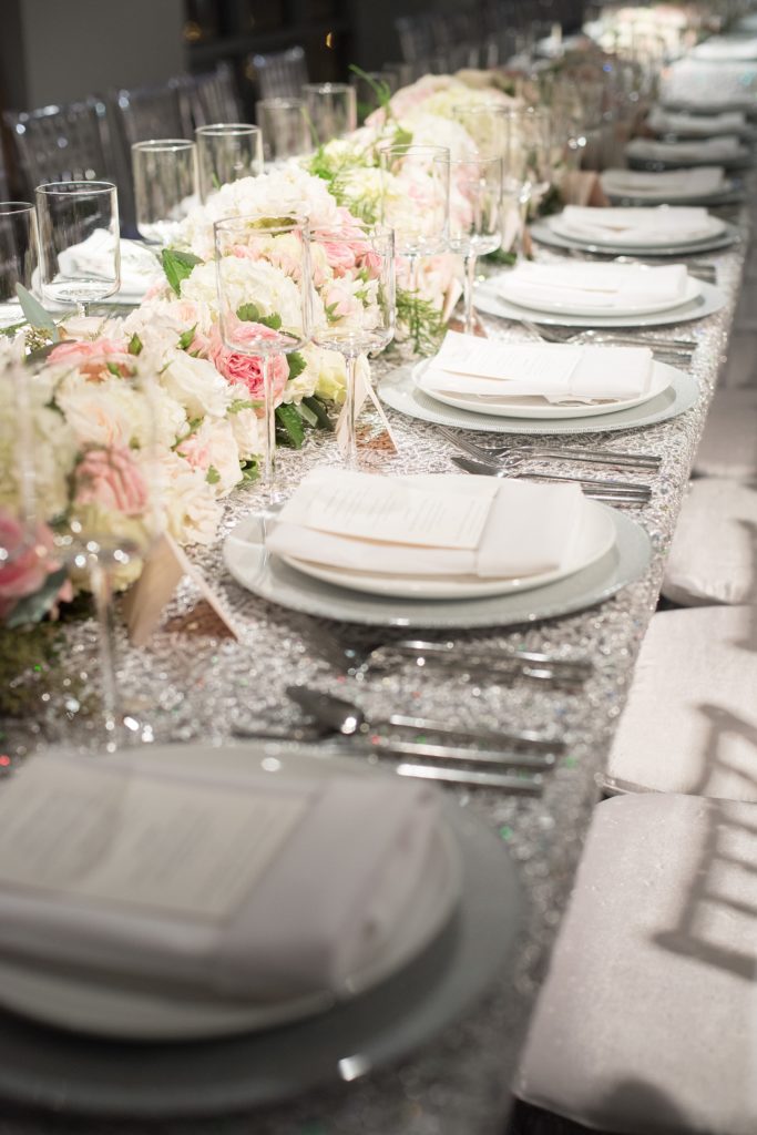 Mikkel Paige Photography wedding photos at The Glasshouses NYC. Luxury rectangle tables with silver sparkly tablecloths and floral garland with pink and white roses at a posh Manhattan venue.