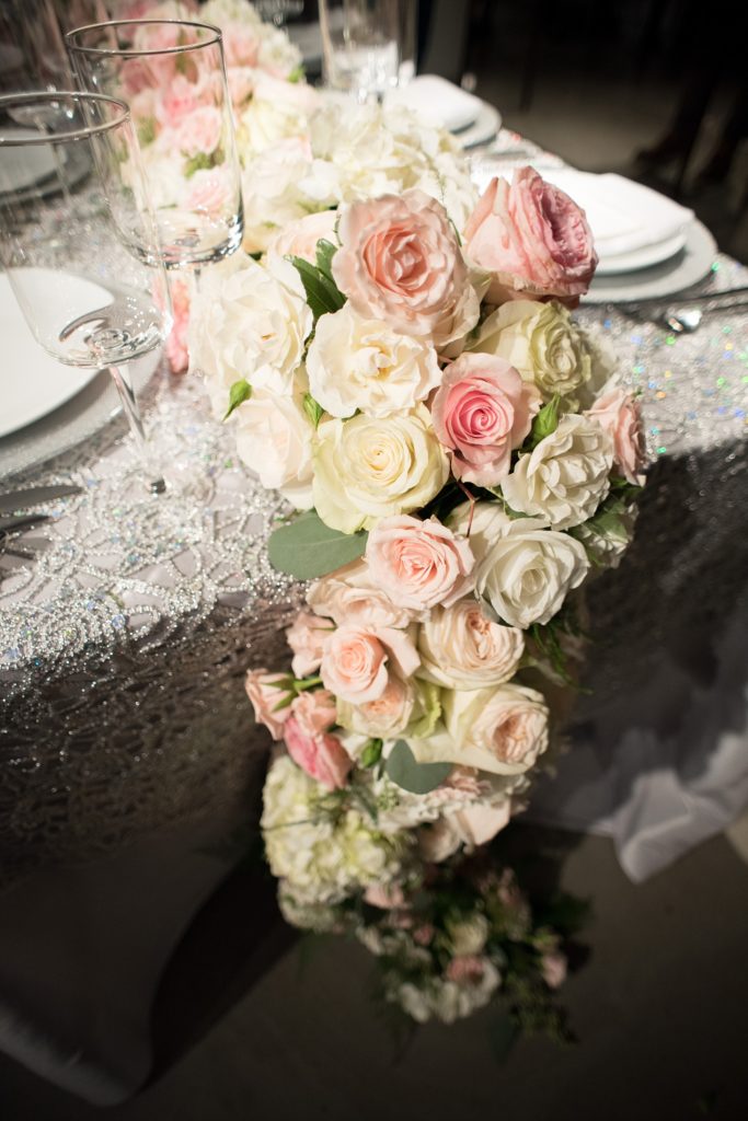 Mikkel Paige Photography wedding photos at The Glasshouses NYC. Luxury rectangle tables with silver sparkly tablecloths and floral garland with pink and white roses at a posh Manhattan venue.