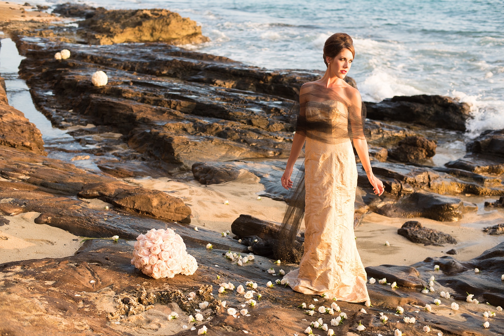 Mikkel Paige Photography photos of a bridal session on beach in Oahu. Golden hour bride with beehive up do, metallic gown and rose pomanders on the lava rock shore.