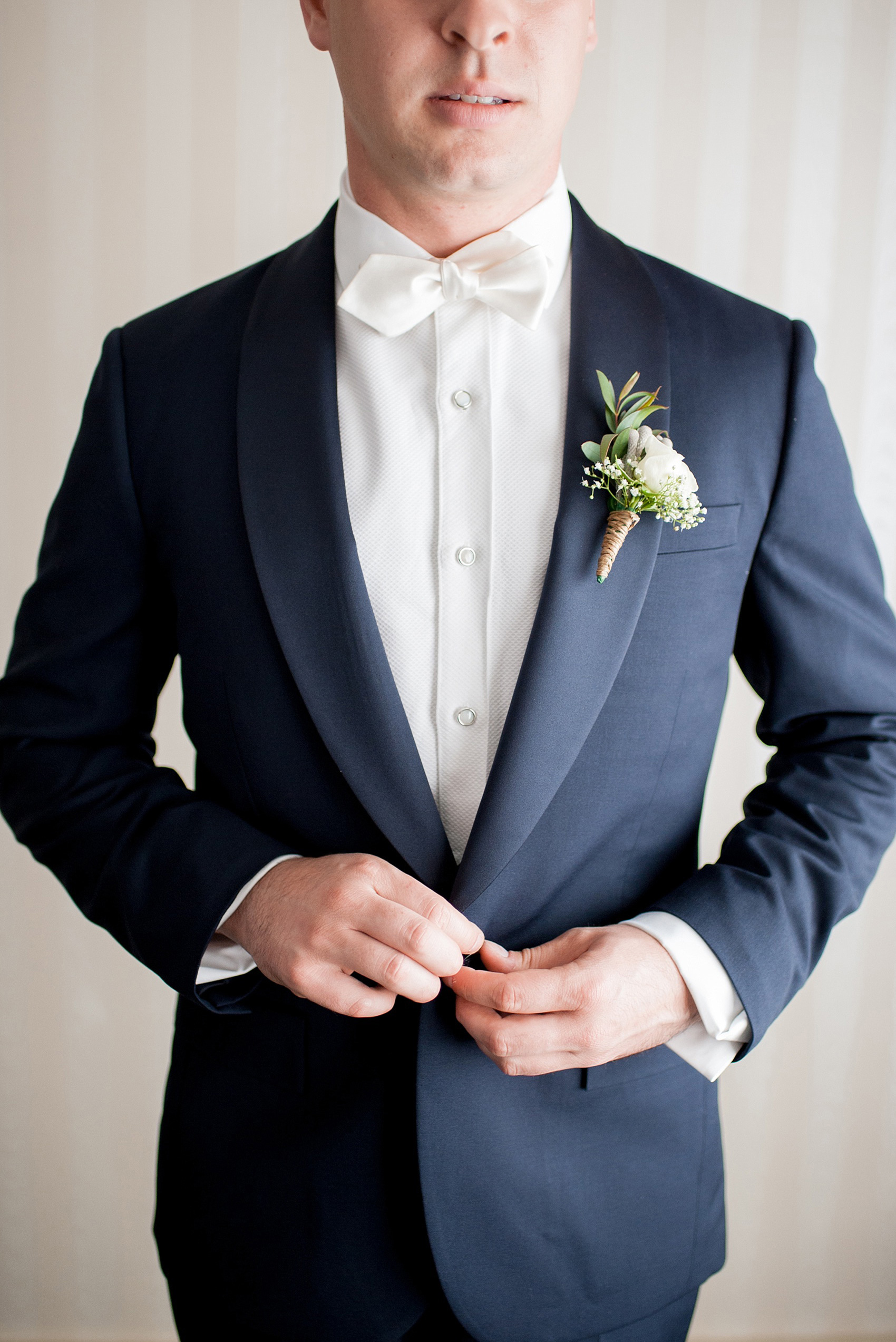 Mikkel Paige Photography photo of a wedding at the Madison Hotel in NJ. Image of the groom getting ready in his navy tuxedo and white bow tie.