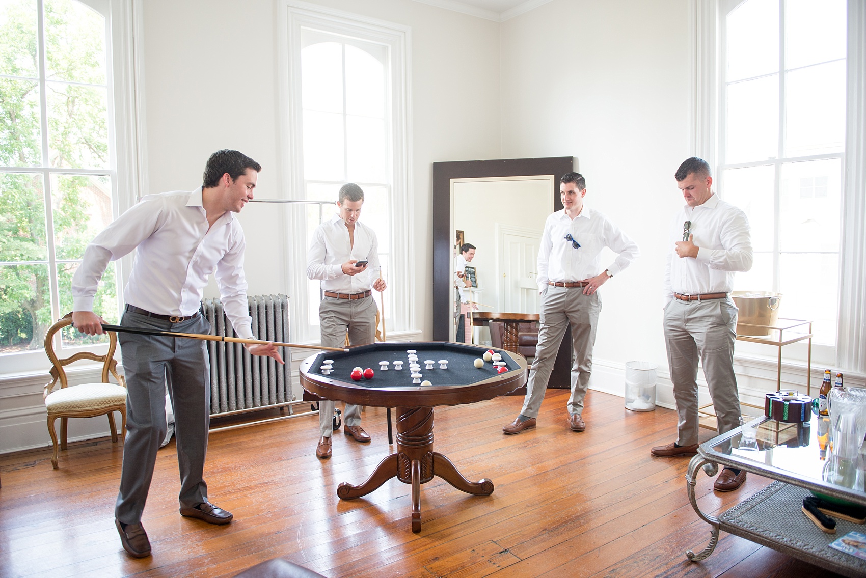 Mikkel Paige Photography wedding photos at The Merrimon-Wynne House in downtown Raleigh. The groom and his groomsmen relax and play table pool before the ceremony.