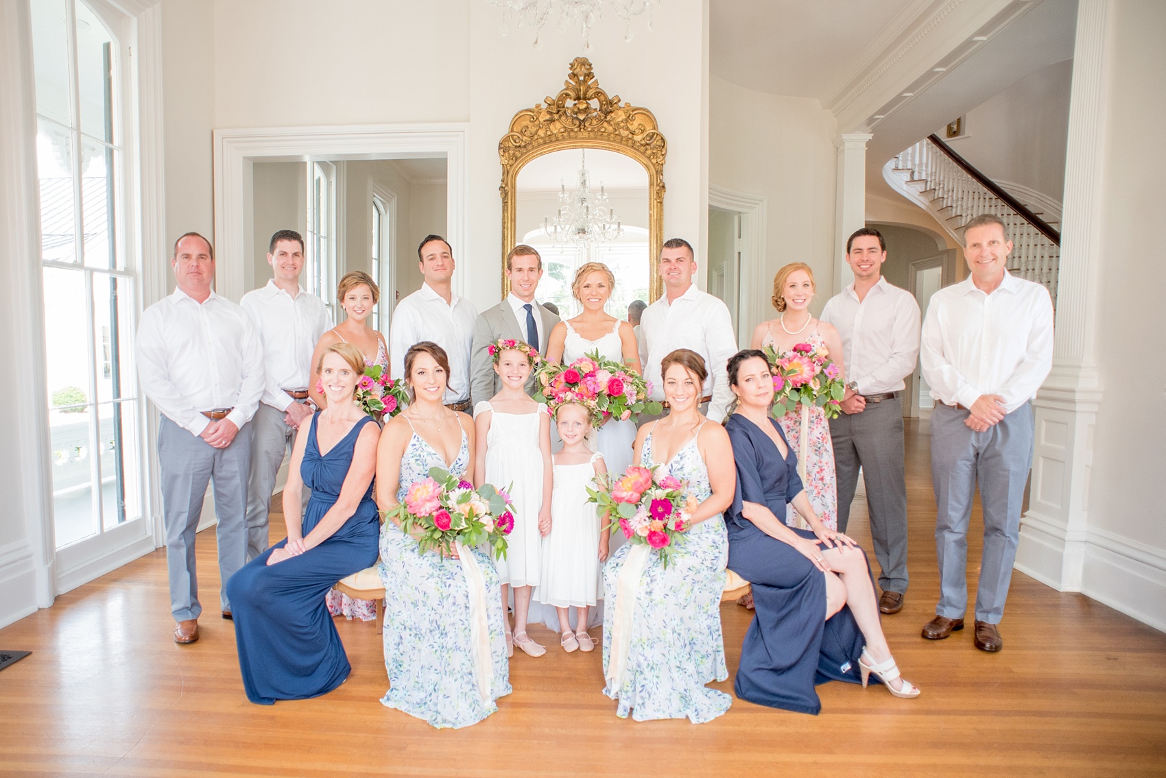 Mikkel Paige Photography wedding photos at The Merrimon-Wynne House in downtown Raleigh. A complete wedding party photo with bridesmaids in floral gowns and the groom's sisters in navy blue dresses.