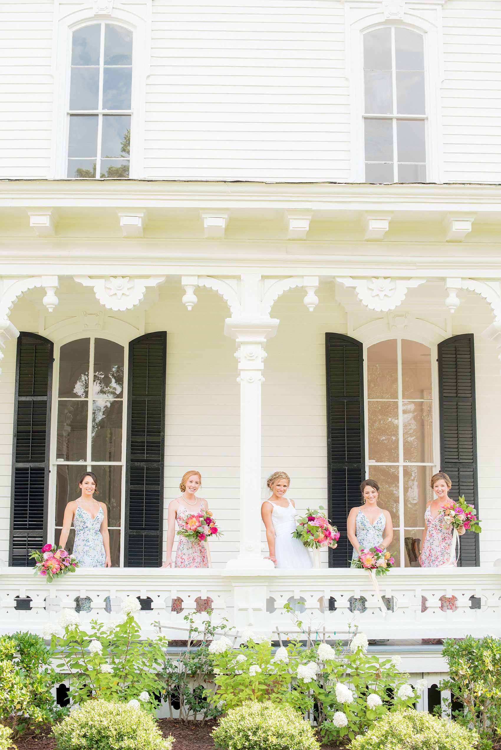 Mikkel Paige Photography wedding photos at The Merrimon-Wynne House in downtown Raleigh. Bridesmaids in floral maxi gowns with colorful pink, orange and green bouquets with peonies, eucalyptus and garden roses by Meristem Floral. 