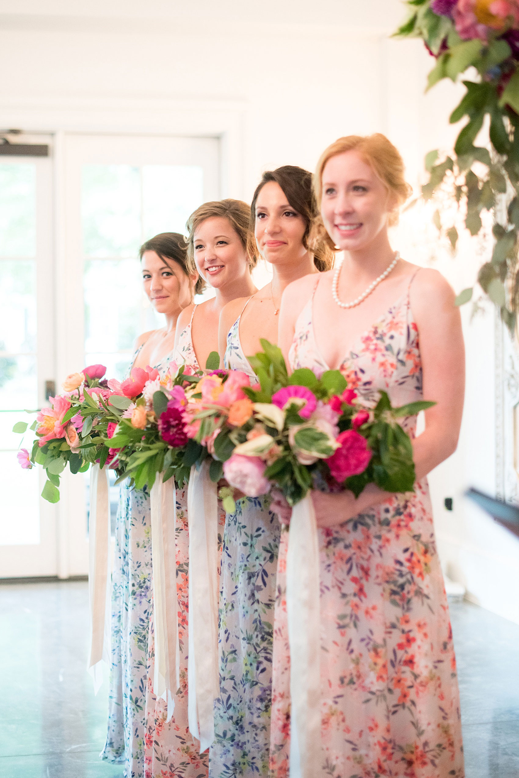 Mikkel Paige Photography wedding photos at The Merrimon-Wynne House in downtown Raleigh. The bridesmaids during the ceremony, pictured in floral maxi dresses with colorful bouquets.