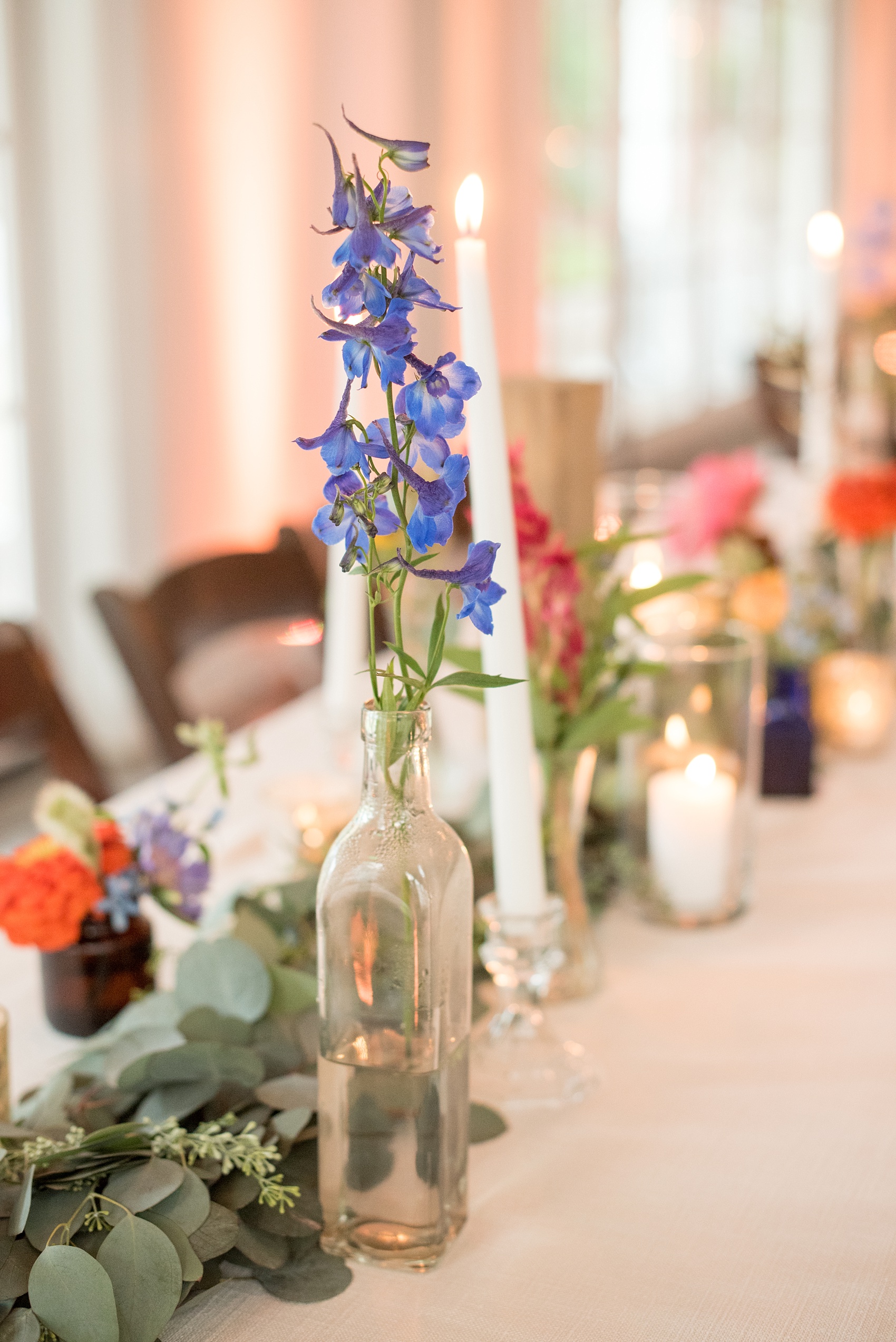 Mikkel Paige Photography wedding photos at The Merrimon-Wynne House in downtown Raleigh. A picture of the carriage house reception with farm tables and rustic details, candlelight, wood table numbers and bud vases with wild flowers.