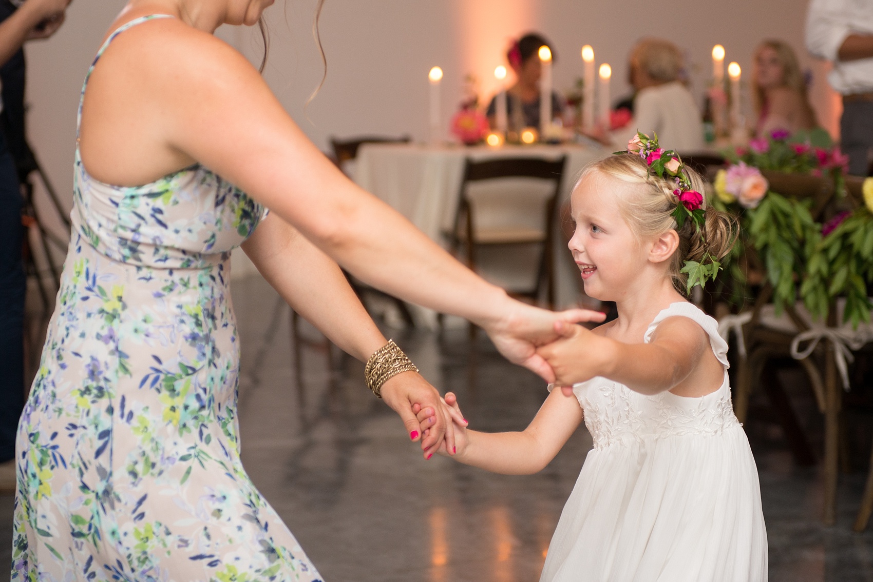 Mikkel Paige Photography wedding photos at The Merrimon-Wynne House in downtown Raleigh. A picture of the carriage house reception. The flower girl dances with a bridesmaid.