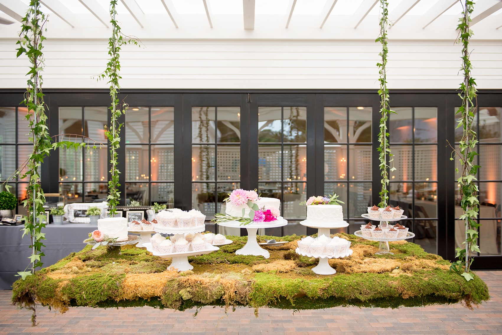 Mikkel Paige Photography wedding photos at The Merrimon-Wynne House in downtown Raleigh. A picture of the moss covered dessert table with multiple white cake and cupcakes.