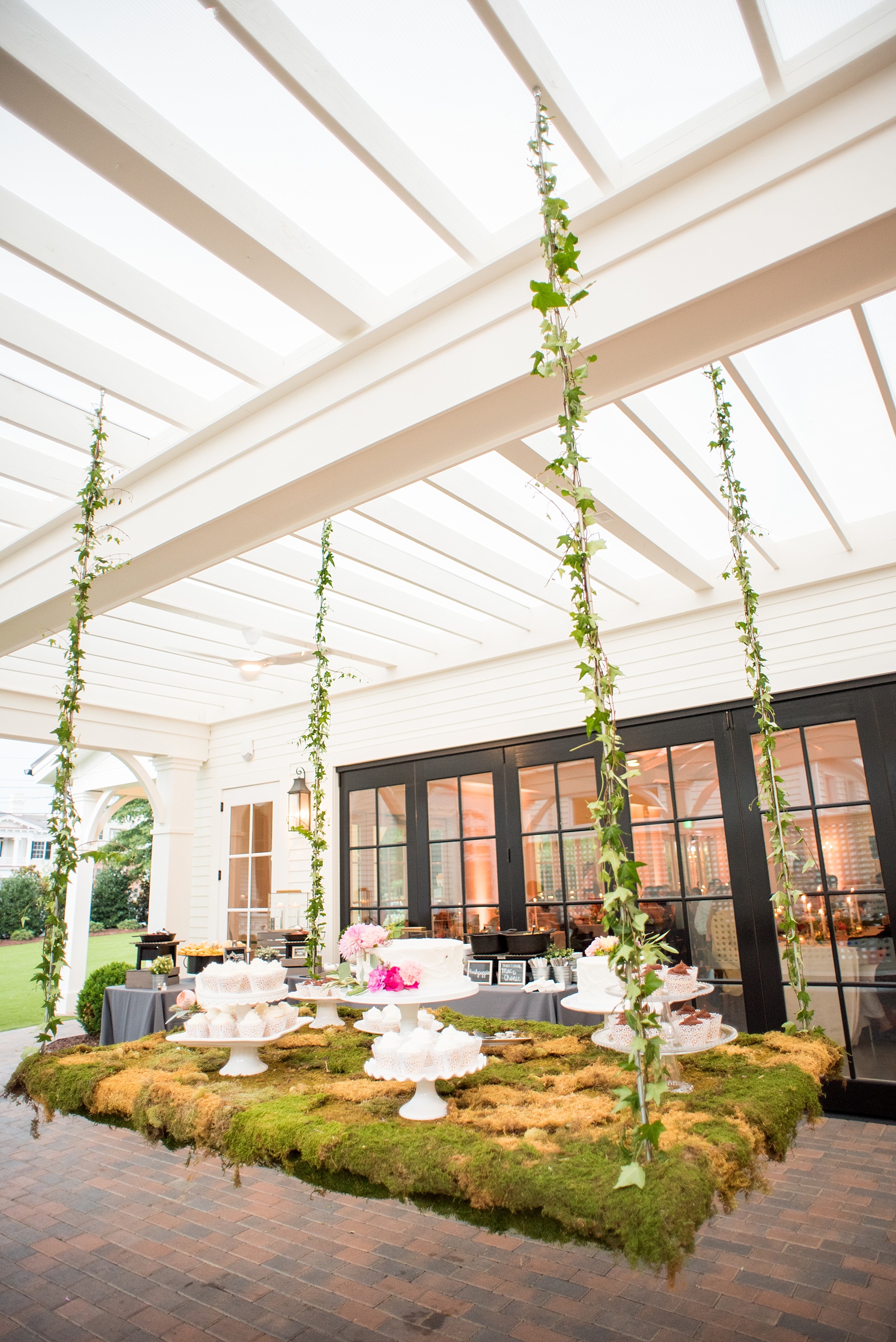 Mikkel Paige Photography wedding photos at The Merrimon-Wynne House in downtown Raleigh. A picture of the moss covered dessert table with multiple white cake and cupcakes.