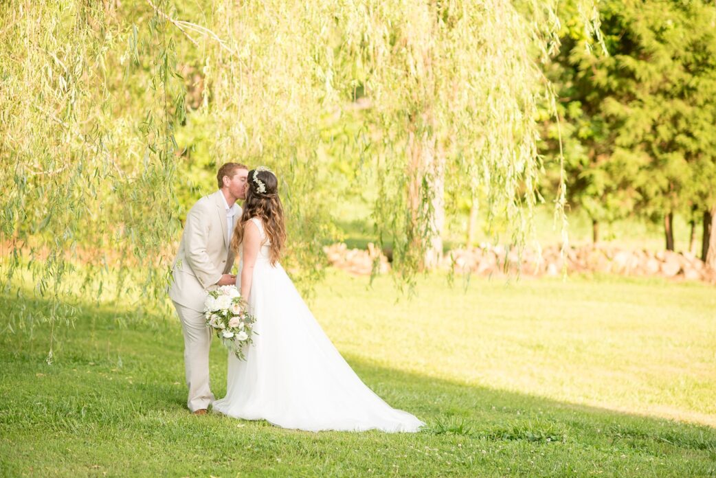 Mikkel Paige Photography photos of a wedding at Spring Hill Manor in Maryland. Bride and groom kiss near a Weeping Willow tree.