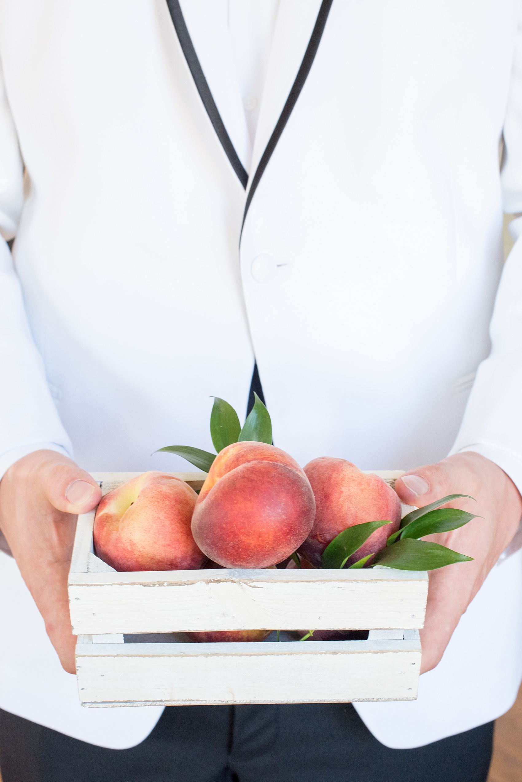 Mikkel Paige Photography wedding photo at The Bradford, NC. The groom holds a white shabby chic box of peaches.