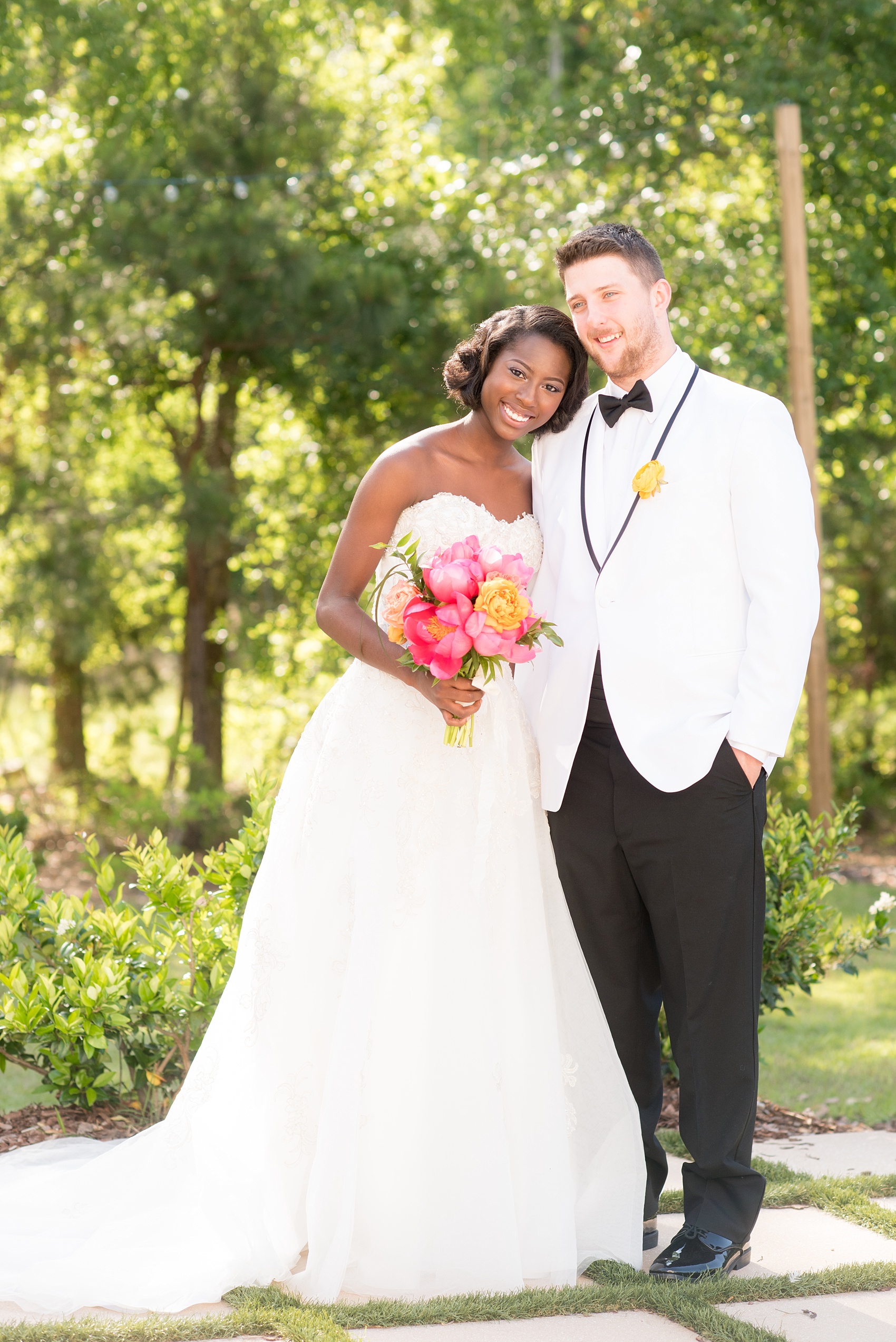 Mikkel Paige Photography photo at The Bradford, NC. Bride and groom of mixed race on the brick and green grass lined exterior patio.