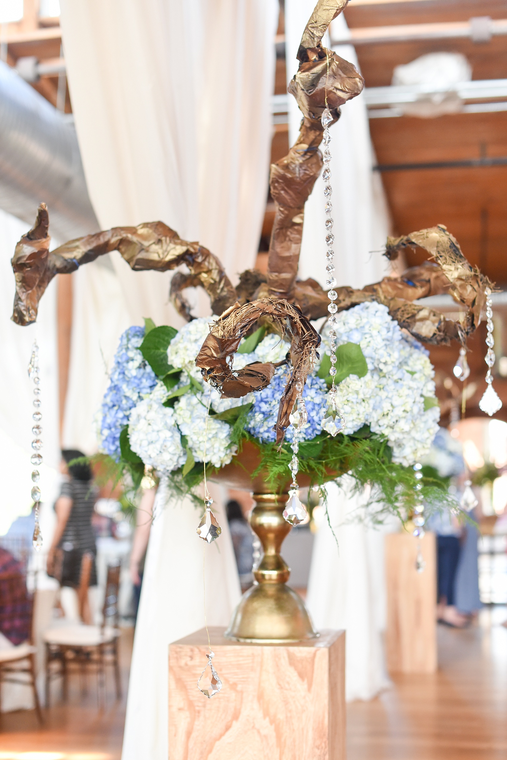 Mikkel Paige Photography photos from The Cotton Room wedding venue in Durham, NC. A beautiful floral centerpiece with greenery and blue hydrangea and crystals hanging off.