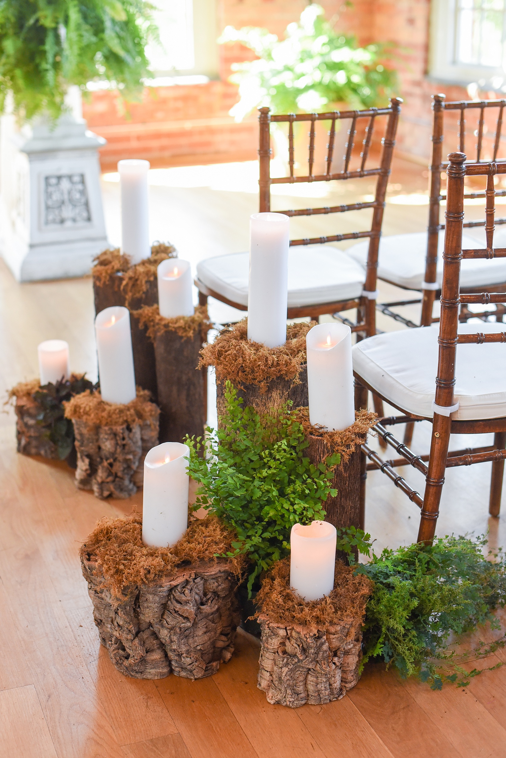 Mikkel Paige Photography image from The Cotton Room wedding venue in Durham, NC. A wooden fairy forest scene of candles and wood tree trunk stumps with moss lined the ceremony aisle.