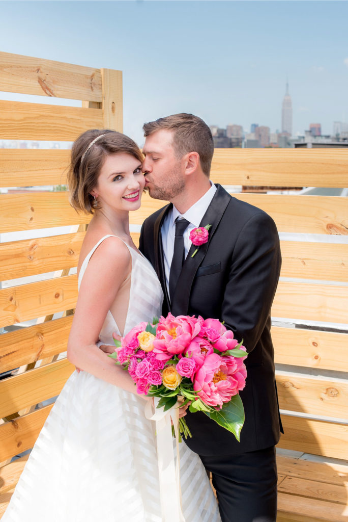 Mikkel Paige Photography photo of Dobbin St Brooklyn wedding. Planning and coordination by Color Pop Events. Rooftop photos in Williamsburg with the Empire State Building and Freedom Tower behind the bride and groom.