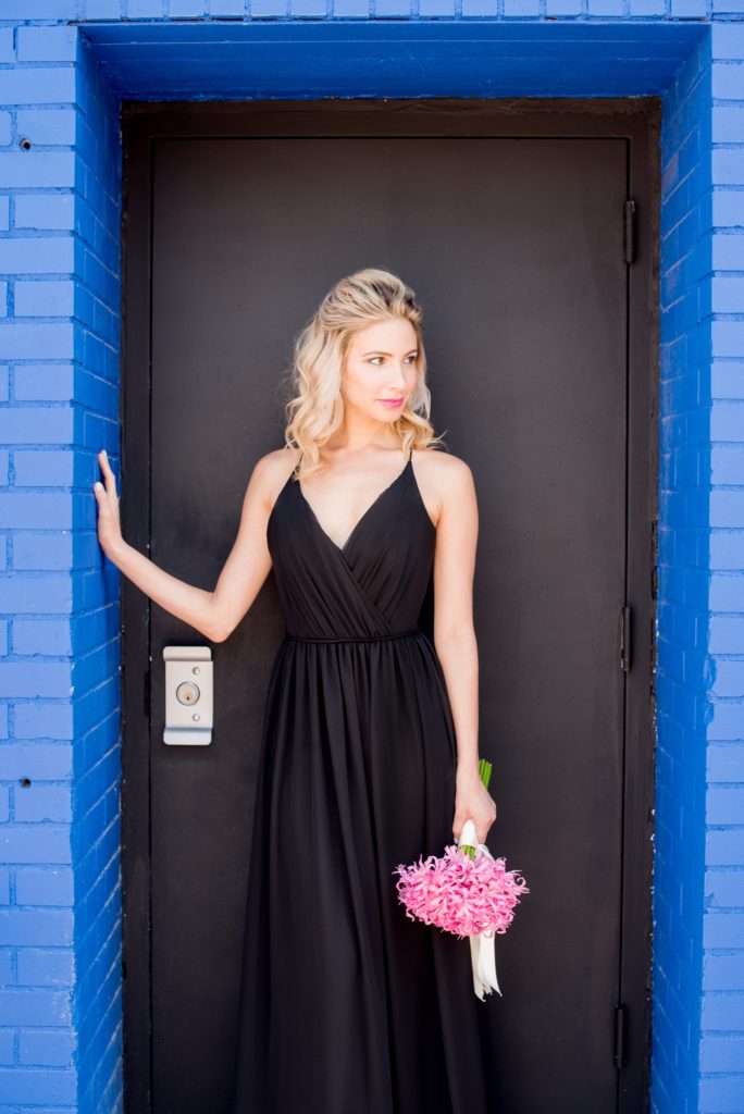 Mikkel Paige Photography photo of Dobbin St Brooklyn wedding. Planning and coordination by Color Pop Events. Black chiffon bridesmaid gown by Hayley Paige Occasions. Image against a bright blue and black. Hair do in a half up bun.